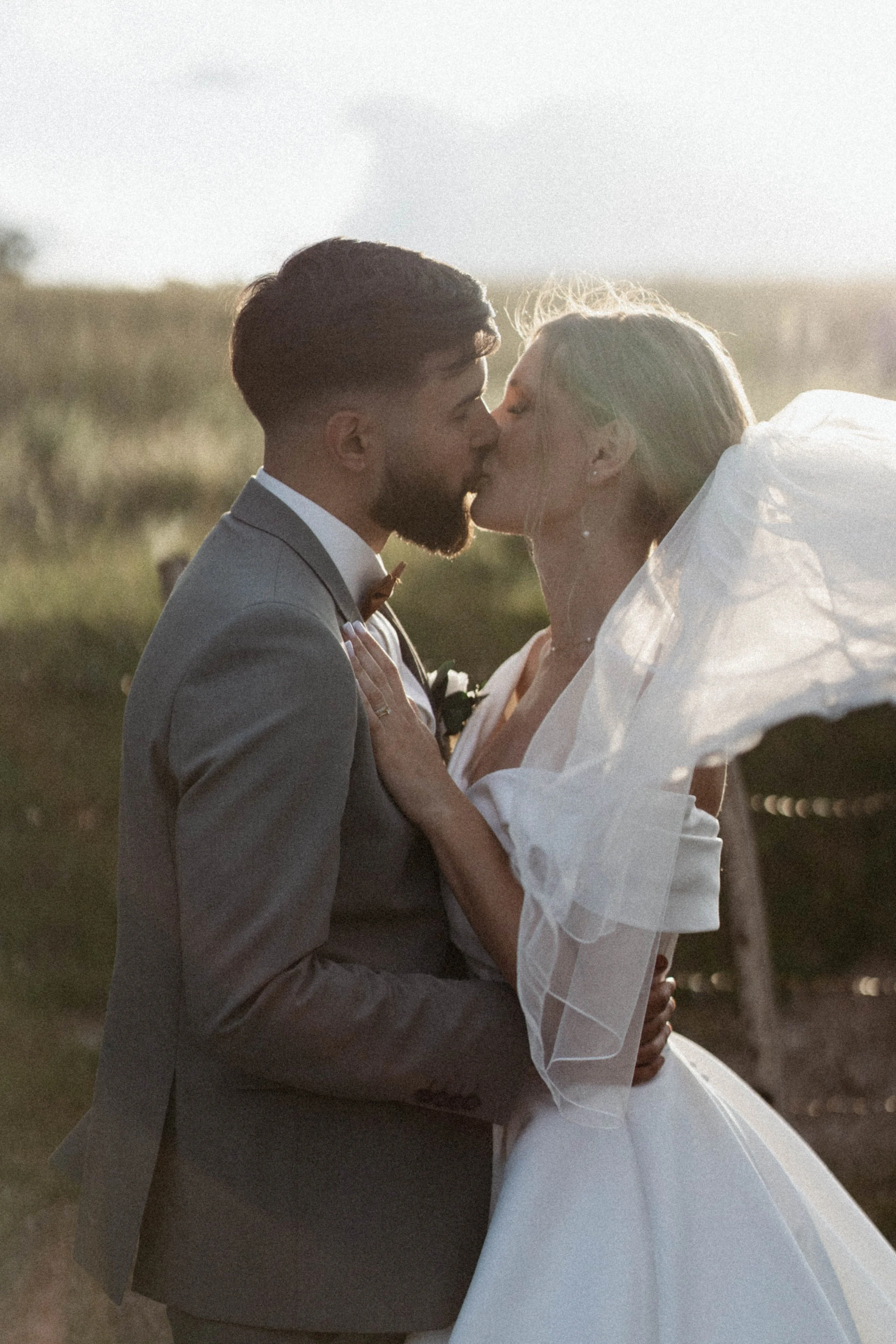 Un couple marié s'embrassant dans un champ lors de leur mariage.