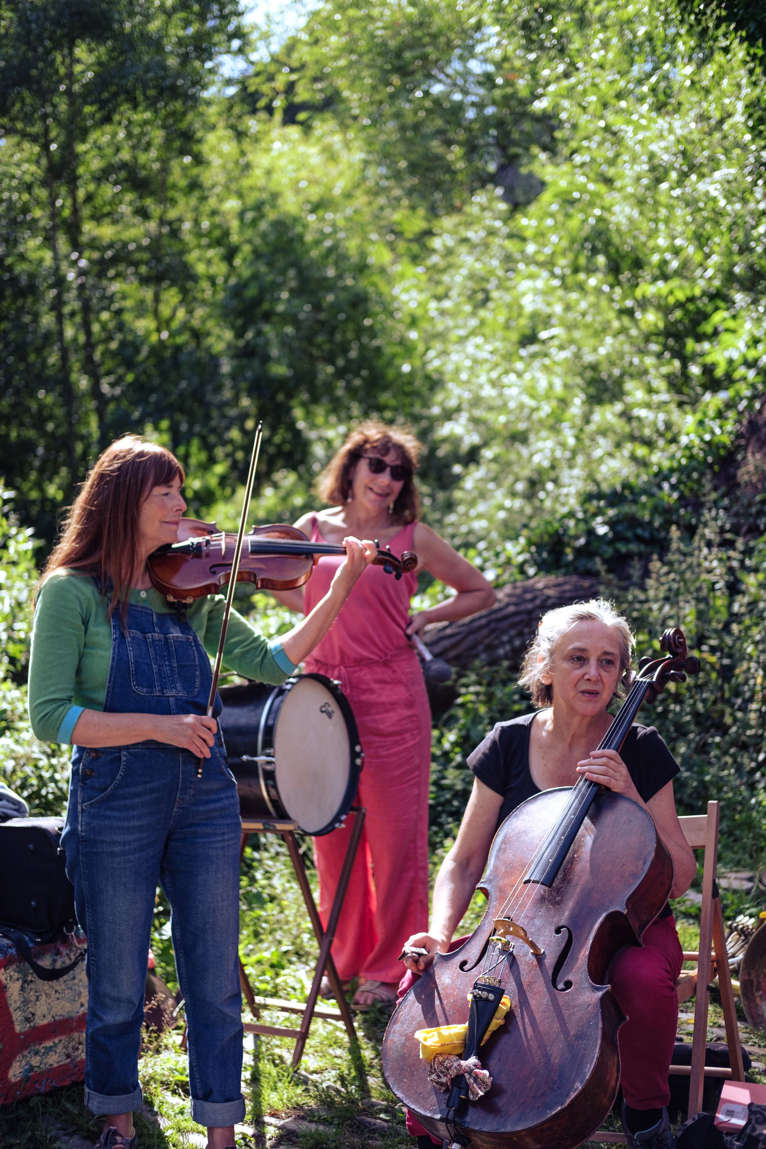 Three musicians perform in a woodland setting