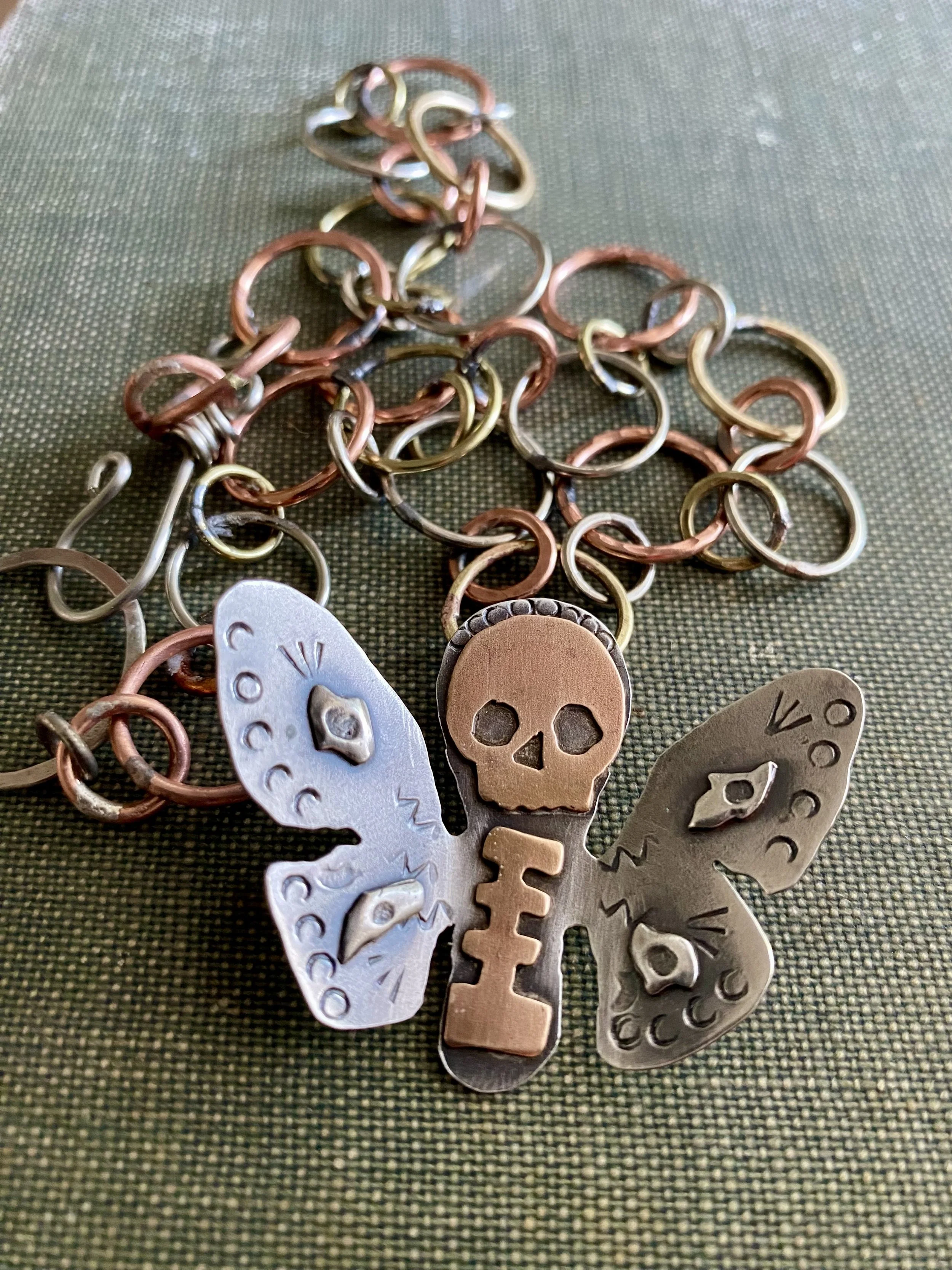 A collection of metallic keychains and rings scattered on a dark green textured fabric surface.