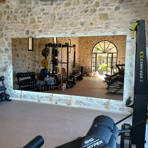 Grand miroir mural sur mesure dans une salle de sport à domicile, mur en pierre apparente
