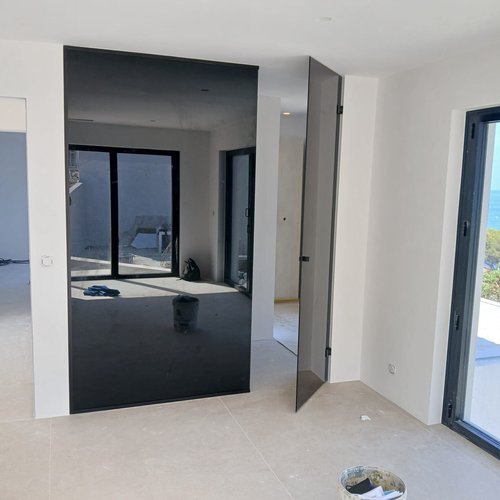 Miroir mural teinté toute hauteur posé dans le séjour d’une villa neuve