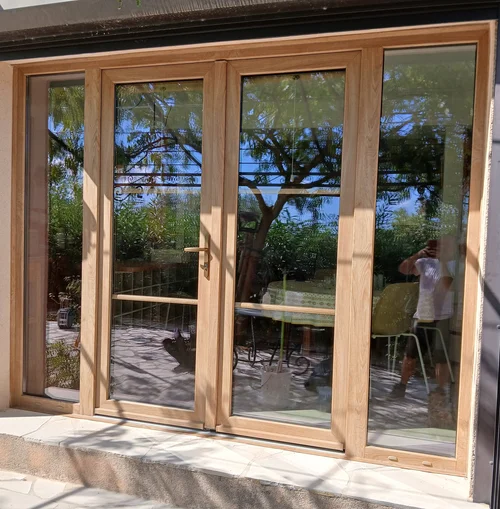 Porte-fenêtre PVC à quatre vantaux imitation bois avec serrure et petits bois intégrés au double vitrage, réalisation Menuiserie Mellin à Bagnols-en-Forêt