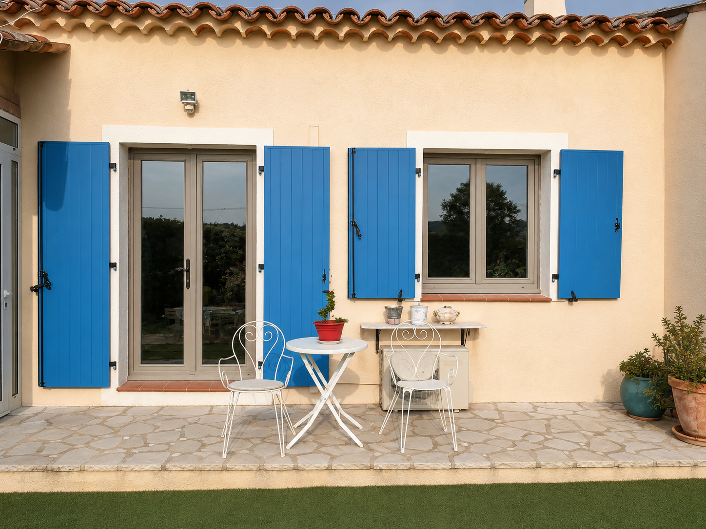 Volets battants bleus sur une maison provençale, portes-fenêtres et terrasse