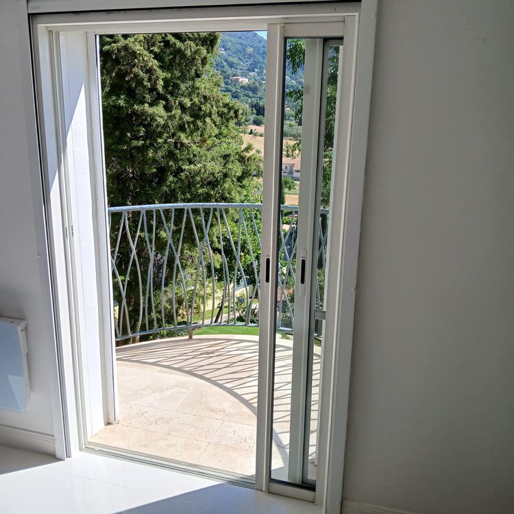 Baie coulissante à galandage en aluminium blanc à deux vantaux, réalisation Menuiserie Mellin à Fayence