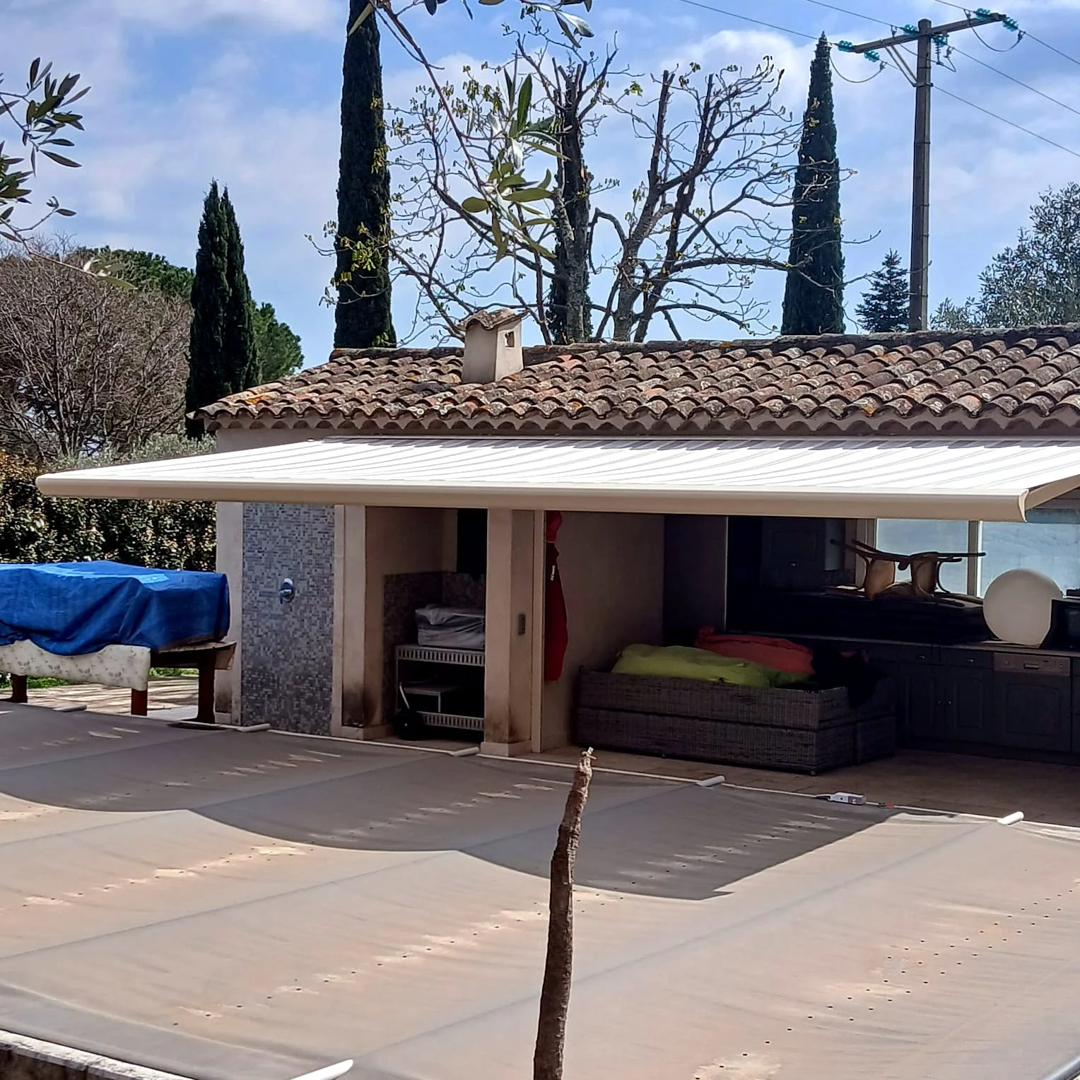 Store banne blanc déployé sur toute la largeur d’une terrasse couverte