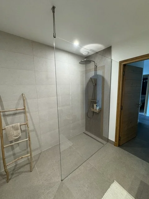 Paroi de douche à l’italienne en verre trempé sur mesure dans une salle de bain carrelée