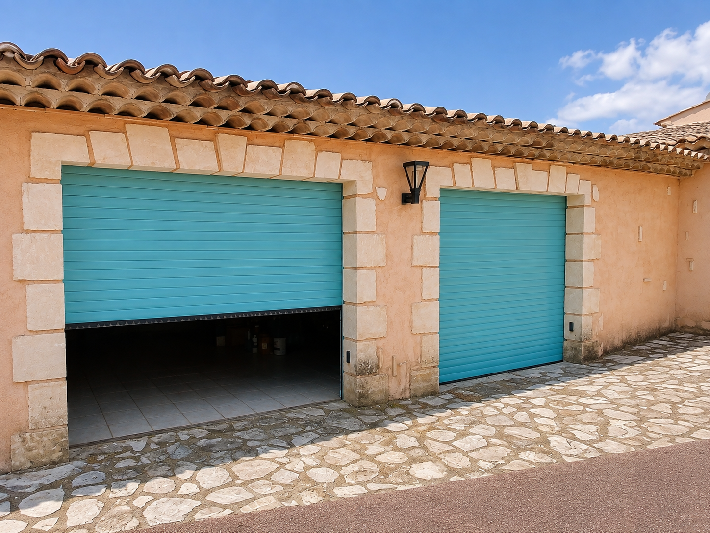 Deux portes de garage enroulables bleu turquoise sur une façade en pierre