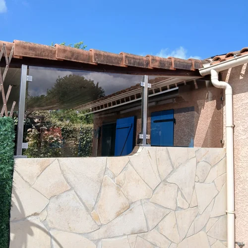 Brise-vue en verre teinté fixé sur un muret de terrasse par platines inox