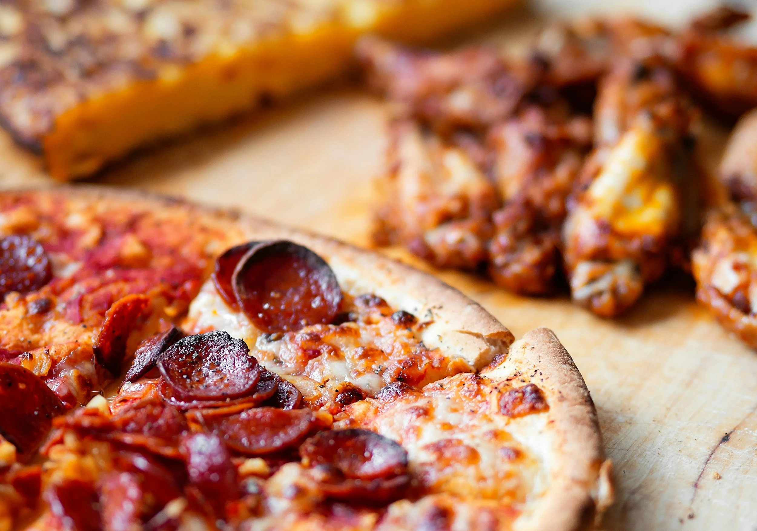 Close-up of two different slices of pizza on a wooden surface.