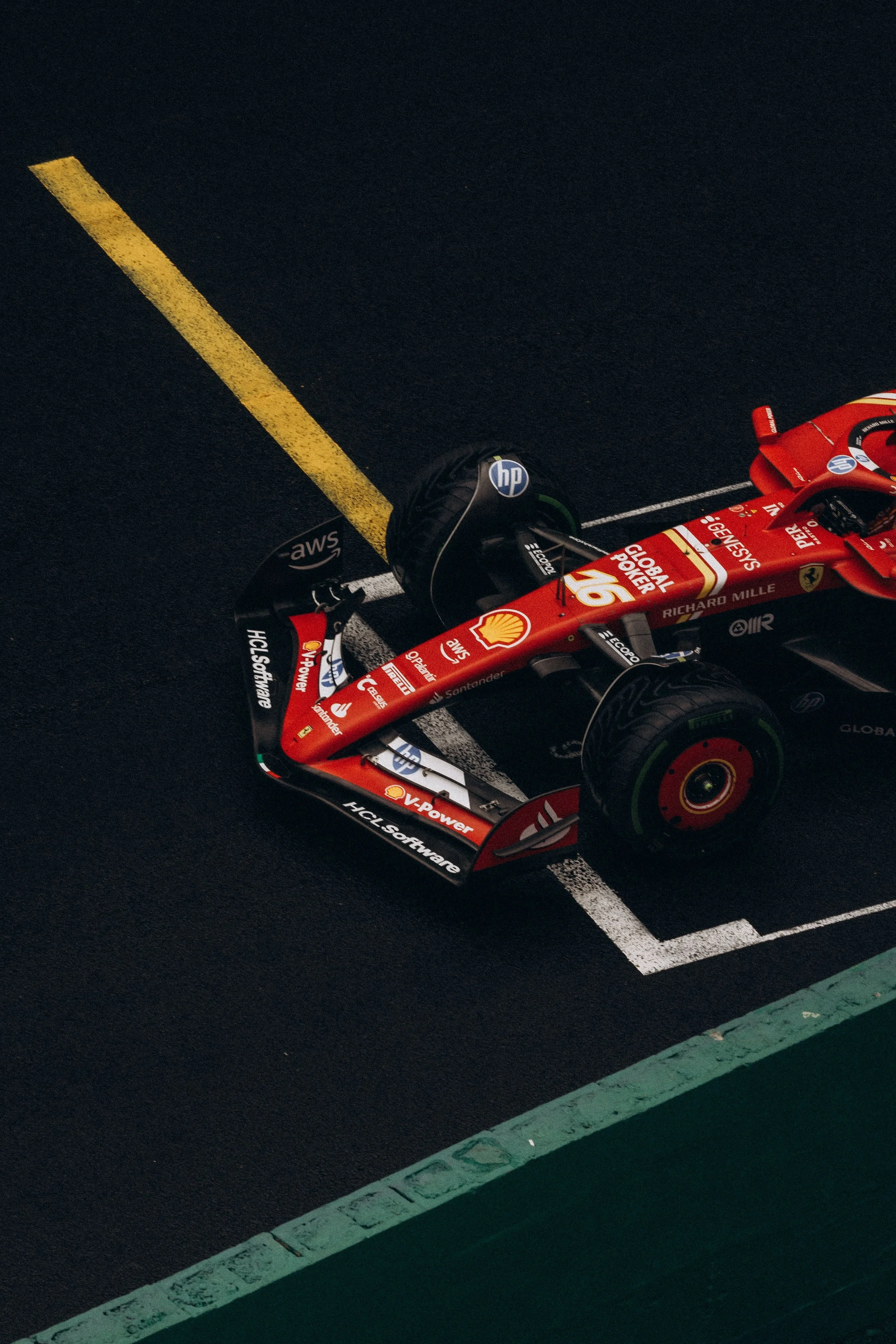 A red Formula 1 race car parked in a designated spot in a parking lot, with visible sponsorship logos and branding on the car.