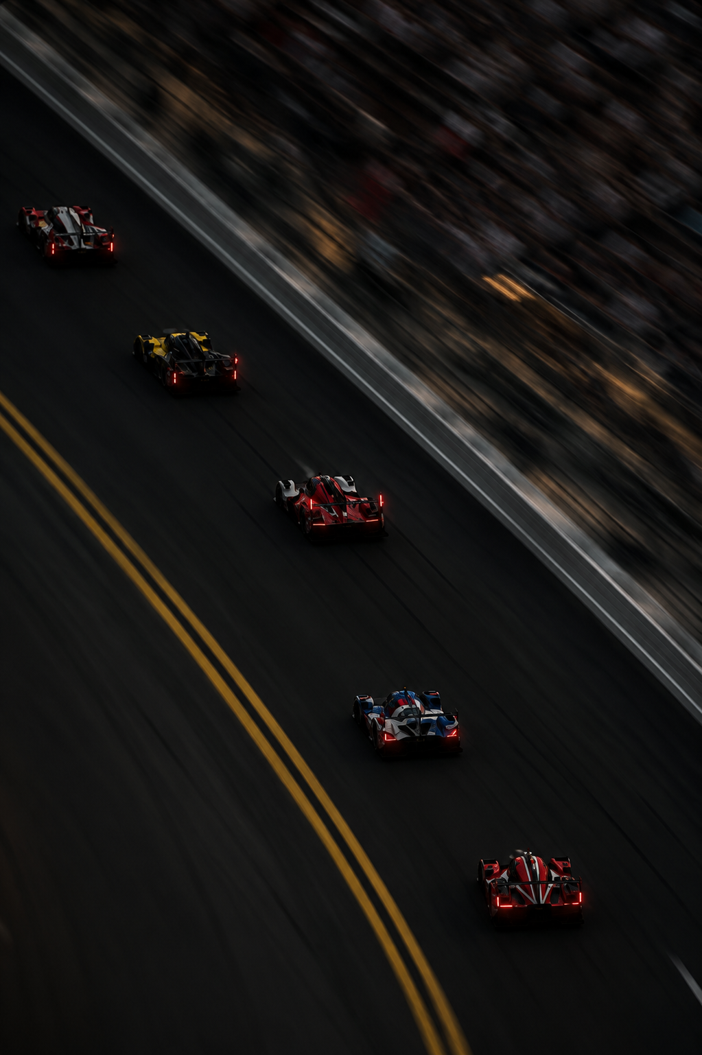 Race cars driving on a dark race track at sunset with blurred audience in the background.