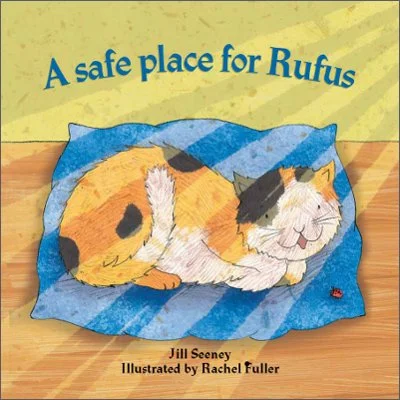 Cover of a children's book titled "A safe place for Rufus" showing a calico cat named Rufus resting on a blue blanket on a wooden floor.
