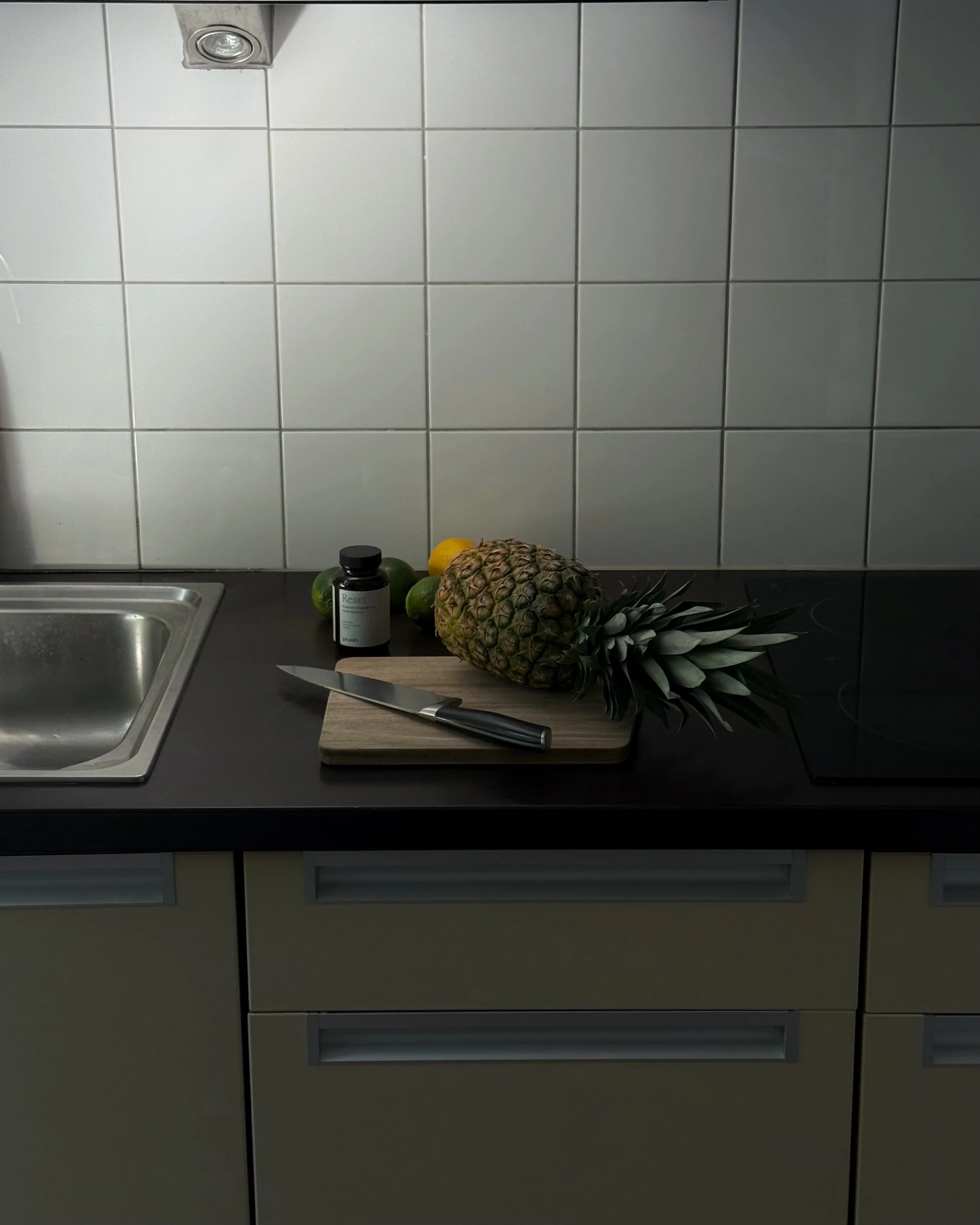 Kitchen counter with fresh fruit, cutting board and wellness supplements.