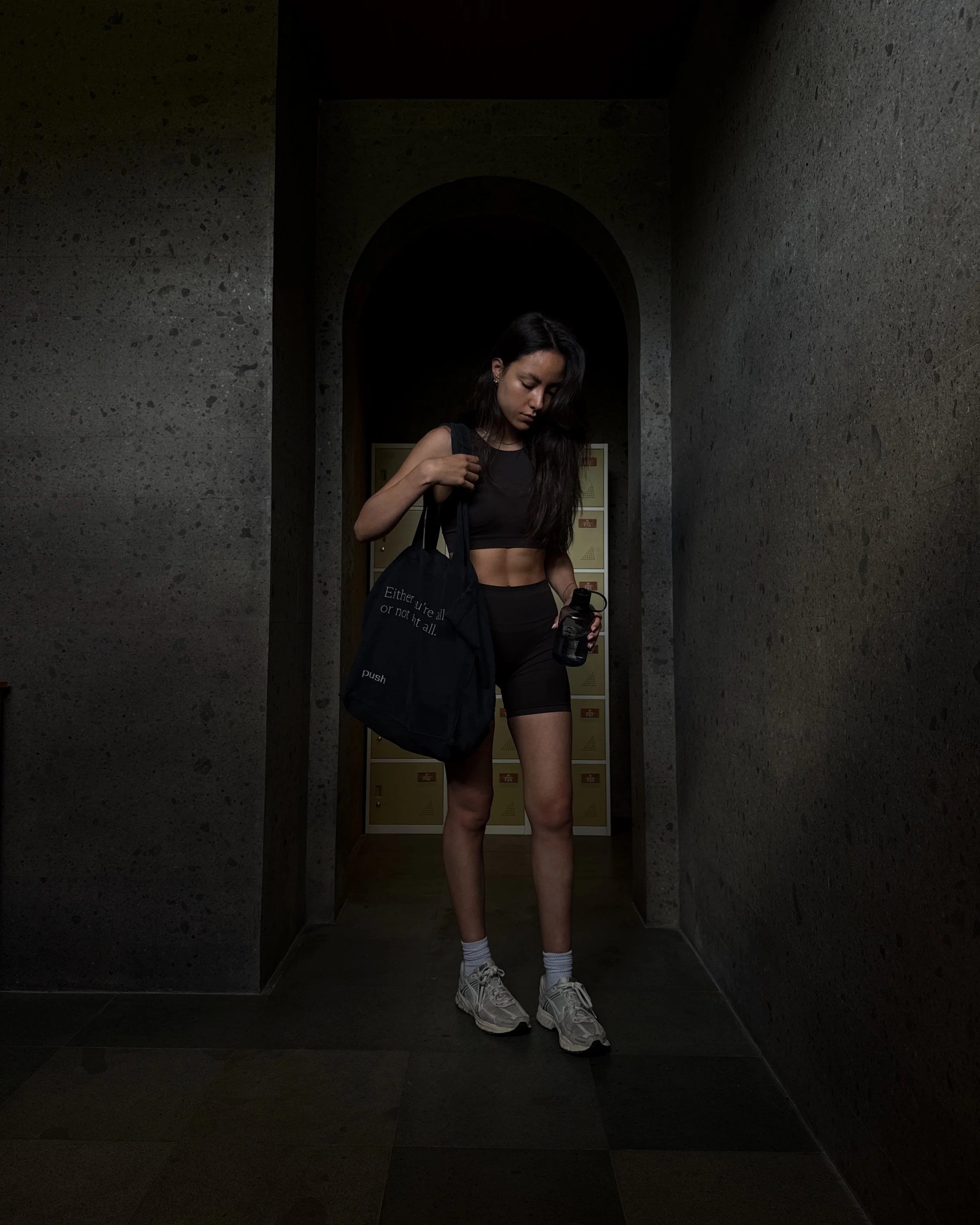 Creator in black activewear holding a gym bag and water bottle.