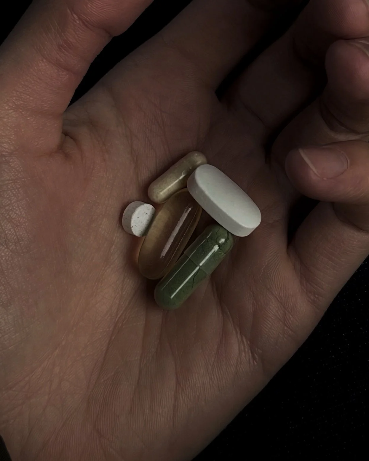 Close-up of assorted daily wellness supplements in a hand.