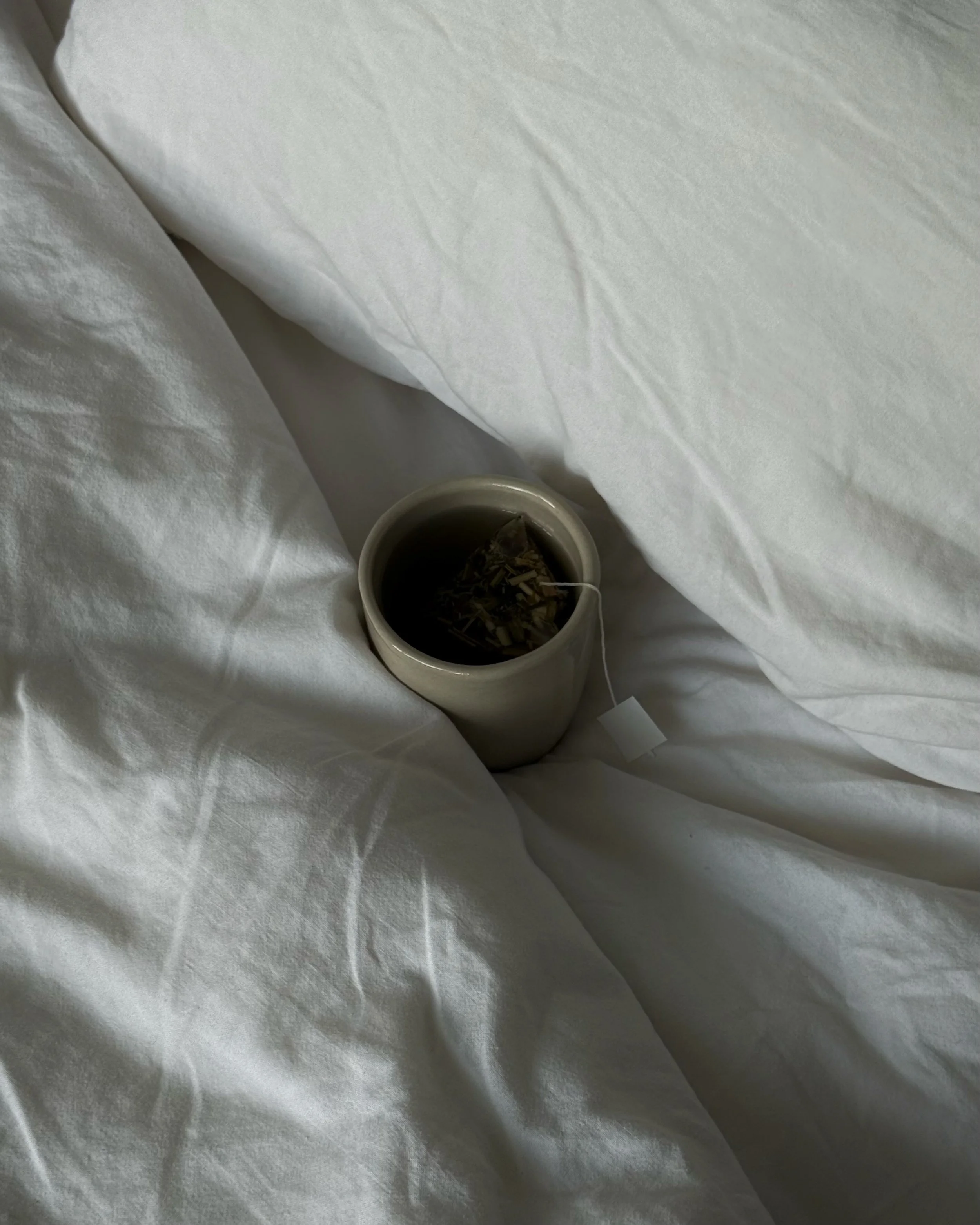 Cup of herbal tea on white bedding.