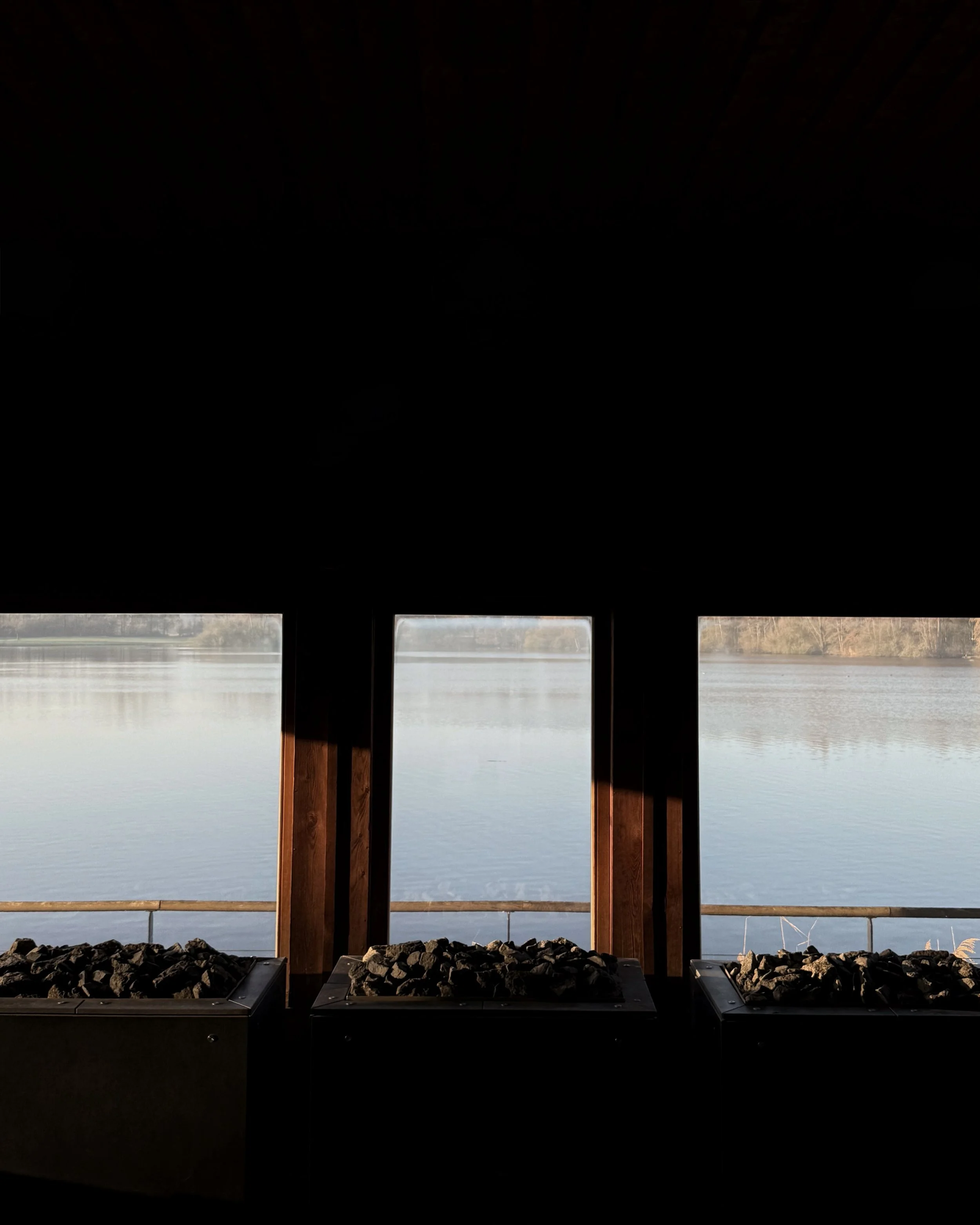 View of a calm lake through the windows of a lakeside sauna.