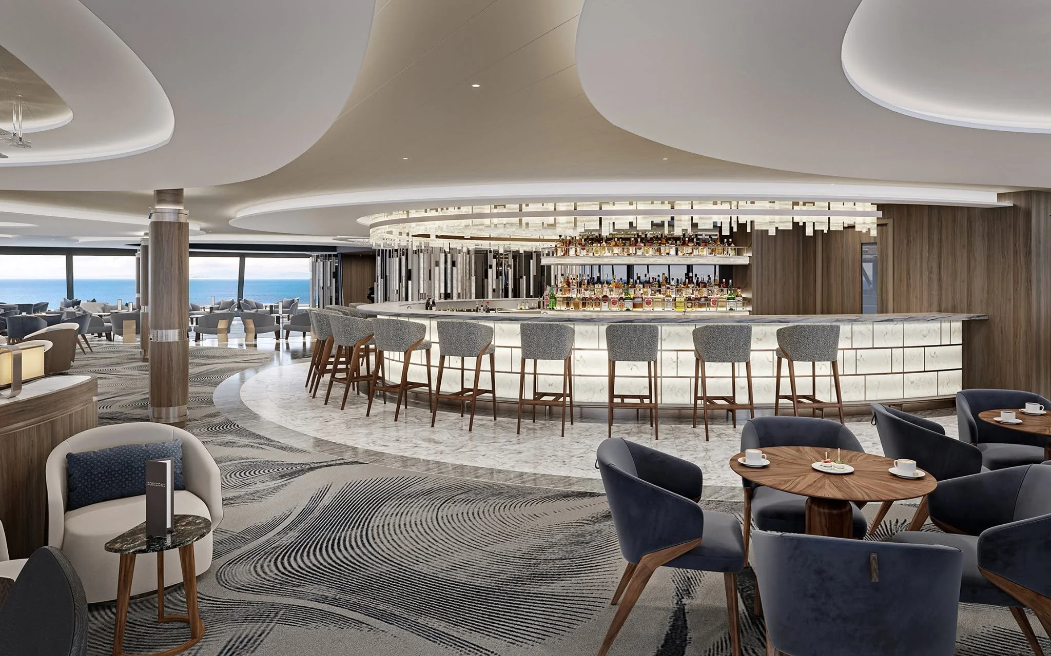 Modern hotel bar with curved ceiling design, a circular bar counter with liquor bottles, and seating area with chairs and tables, overlooking the ocean through large windows.