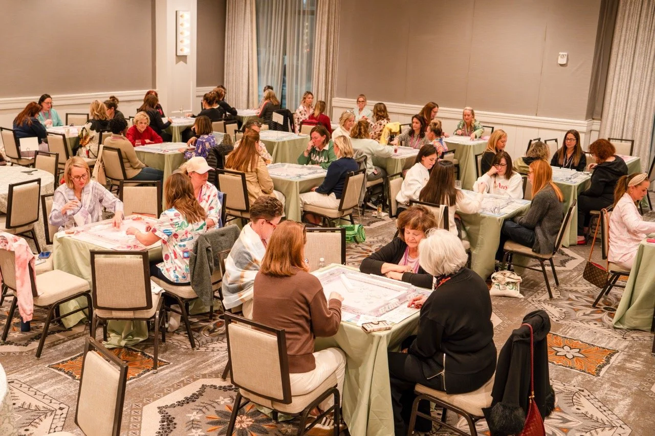A large room filled with women sitting at tables playing American Mahjong.
