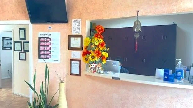 Reception desk with a floral arrangement, computer, and hand sanitizer in a medical office.
