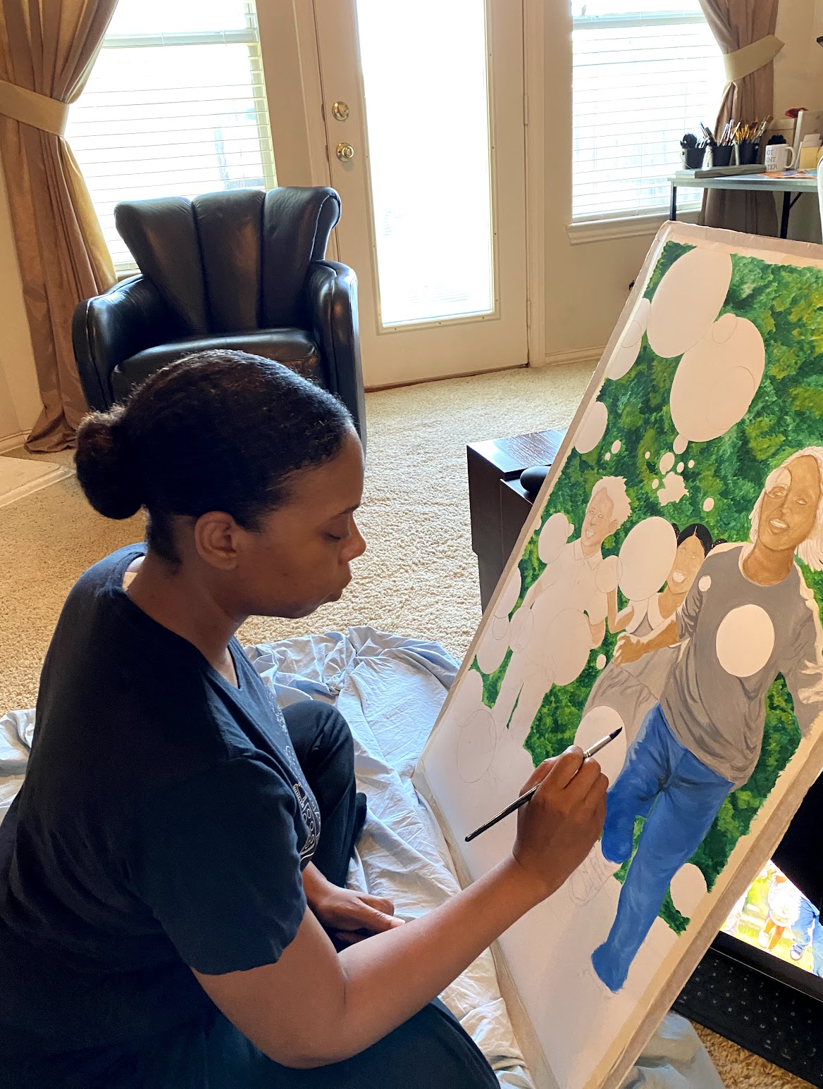 A woman is painting a portrait of four women on a canvas, capturing their expressions and clothing. She is sitting on the floor in a living room near a door with windows, with a leather armchair and a small table visible in the background.