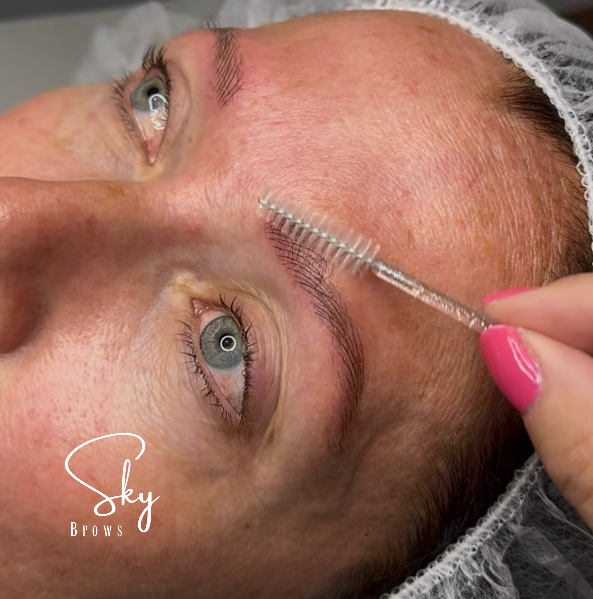 Close-up of a woman's face lying down, with focus on her eye, eyebrow, and forehead. She has light skin, green eyes, and brown hair, partially covered with a hairnet. The text "sky Brows" and "Beauty" are overlaid on the image.