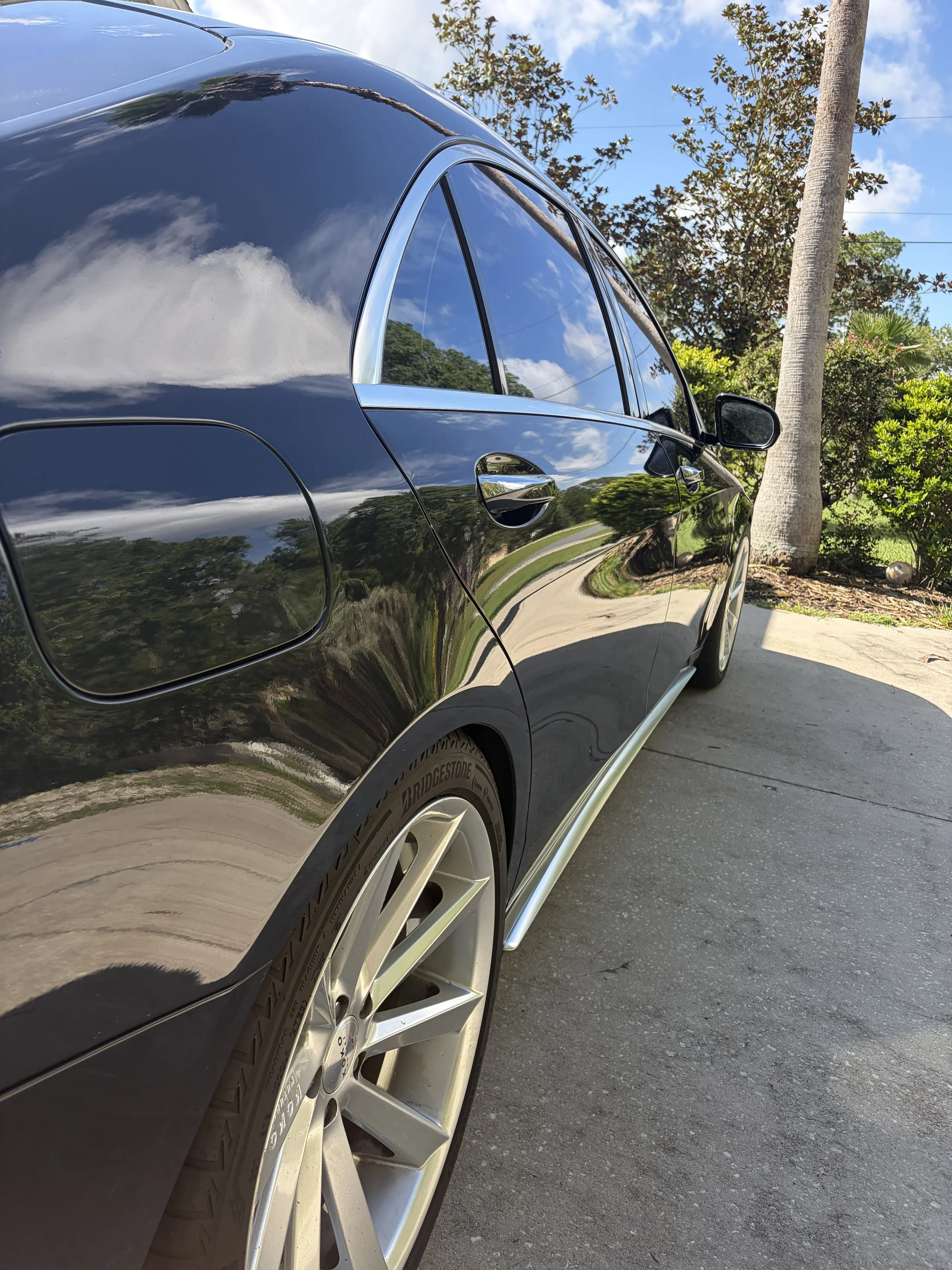 Exterior of a professionally detailed black sedan with a glossy, mirror-like finish after a premium auto detailing service.