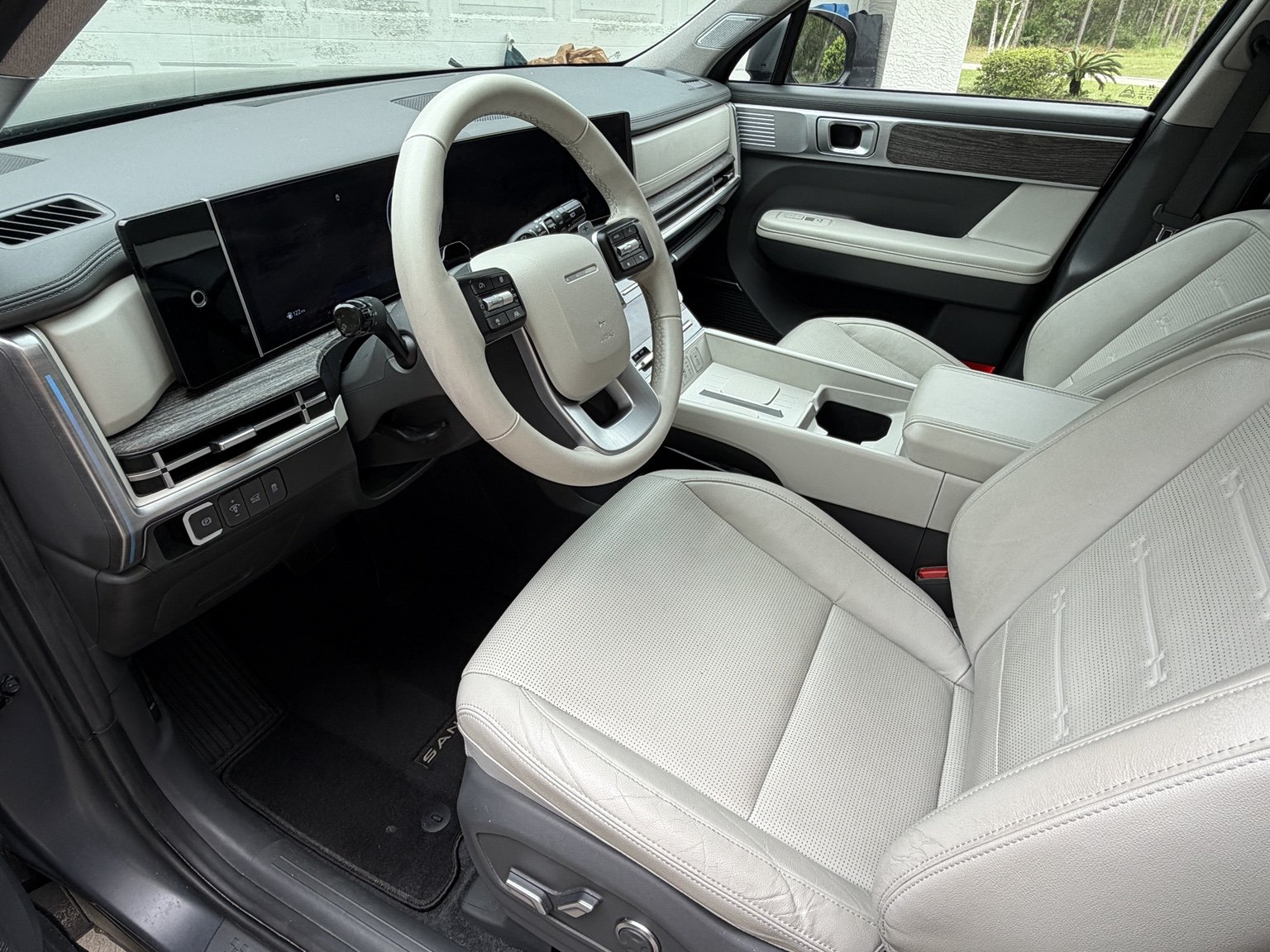 Interior of a modern vehicle with off-white seats, a white steering wheel, and a digital dashboard.