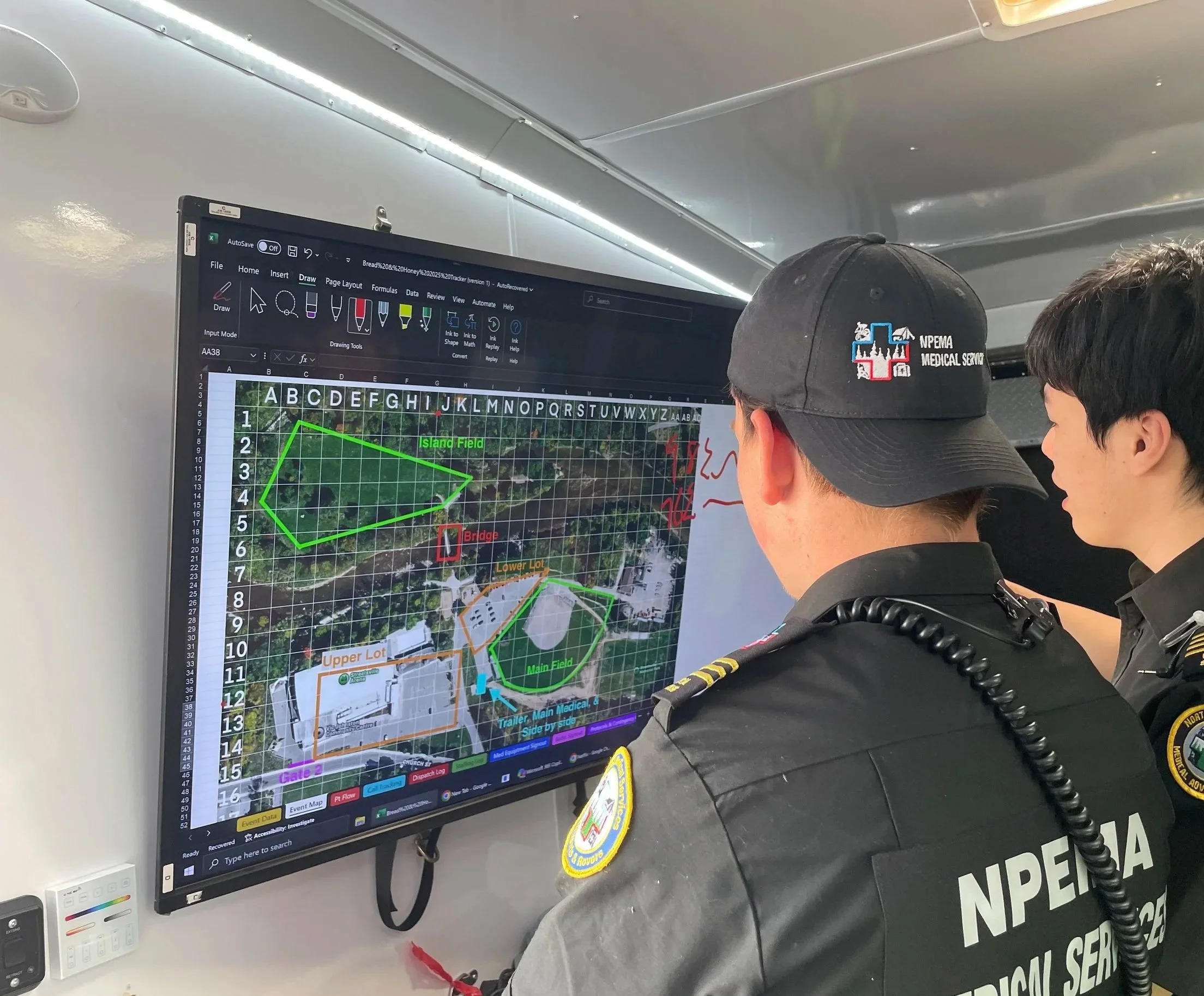 Medical response team members review an event field map displayed on a monitor inside a mobile command vehicle.