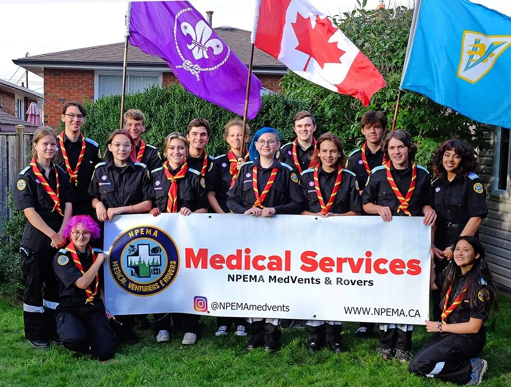 NPEMA MedVents and Rovers youth group in uniform holding a banner and Canadian, Scouting, and venturer flags