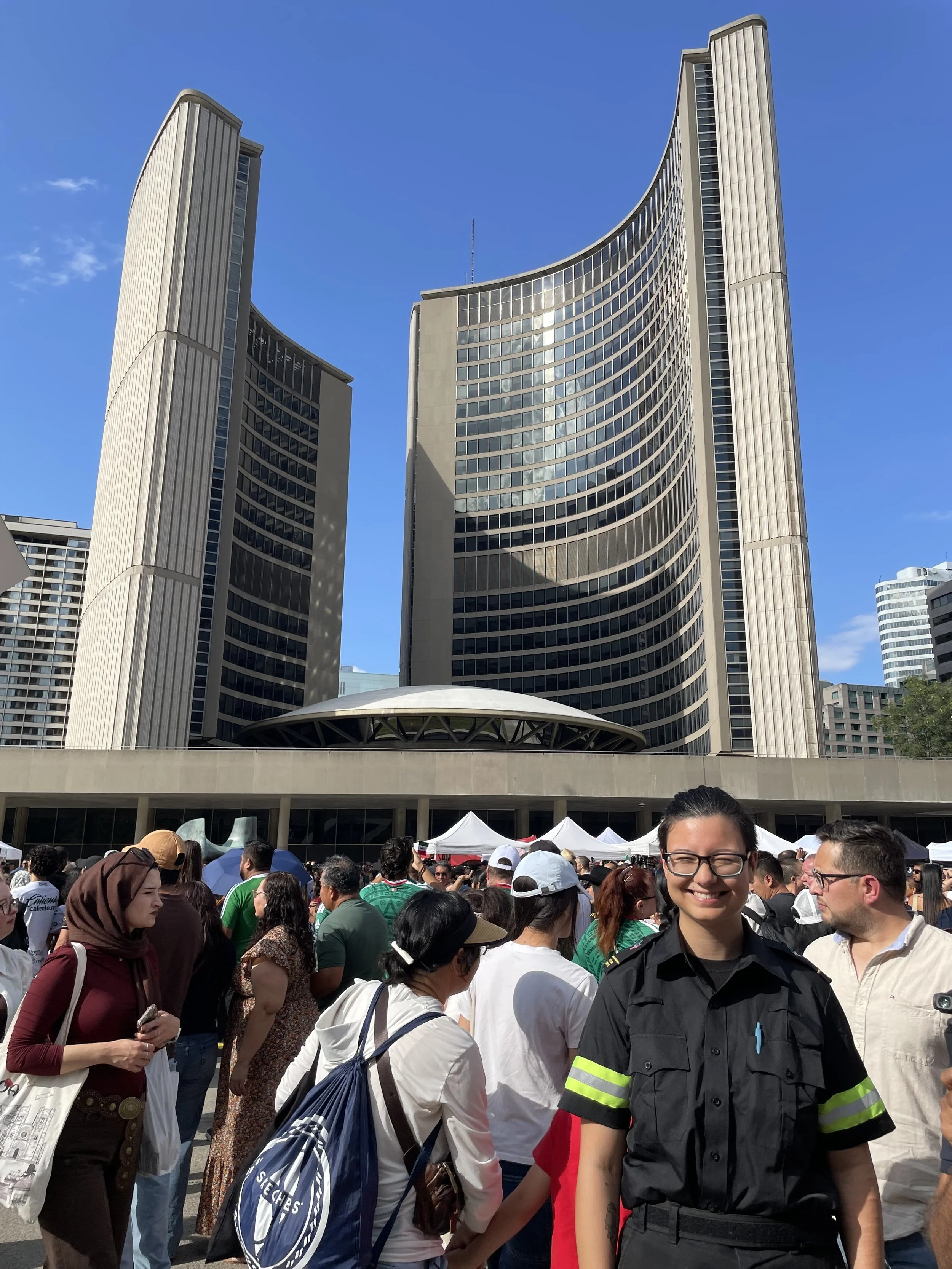 Crowd gathered outside a modern high-rise building with curved architecture under a clear blue sky