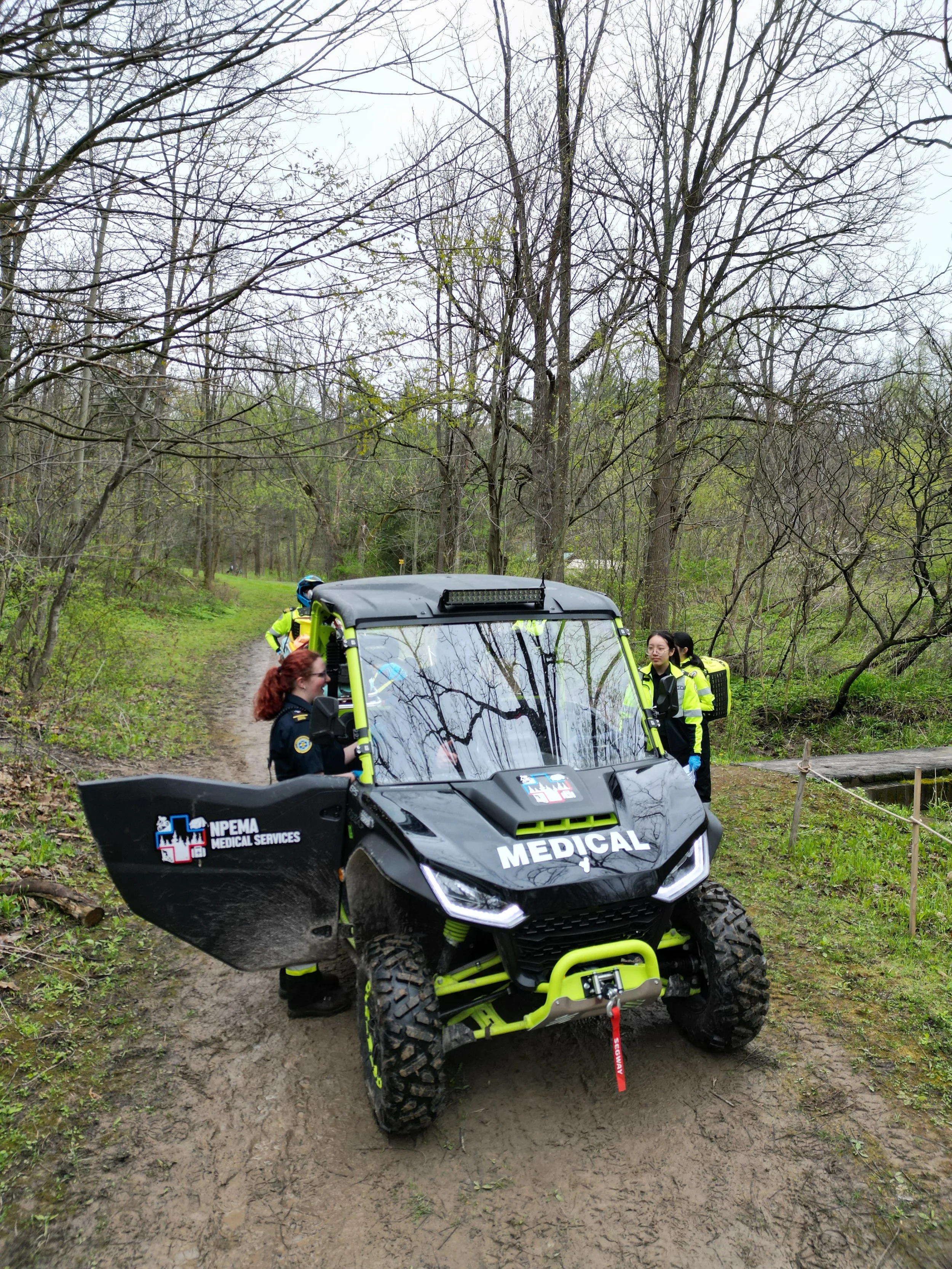 Medical all-terrain vehicle with emergency responders on a wooded dirt trail