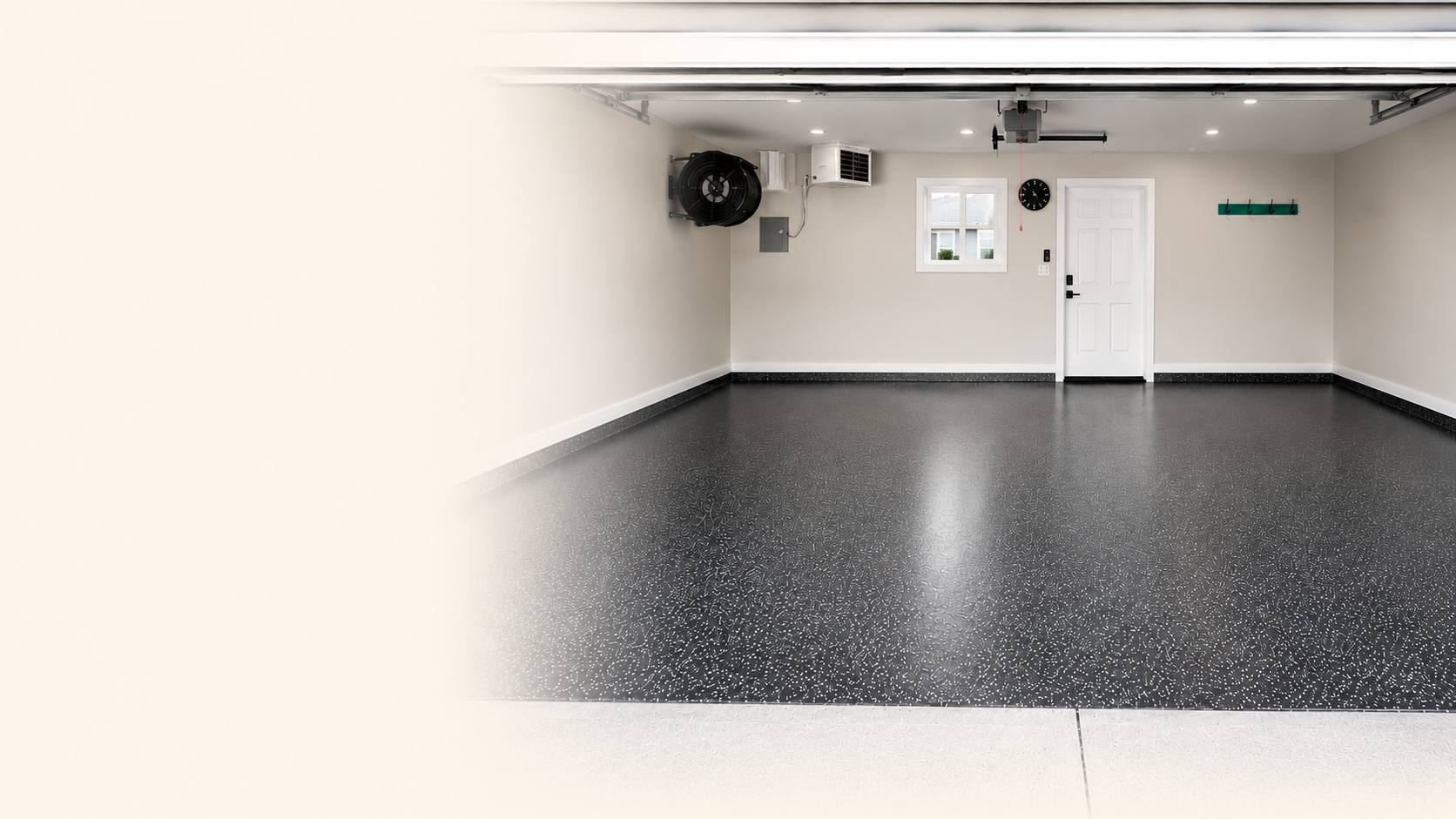 Empty garage with a black speckled epoxy floor, white walls, small window, wall clock, coat hooks, and a garage door opener.