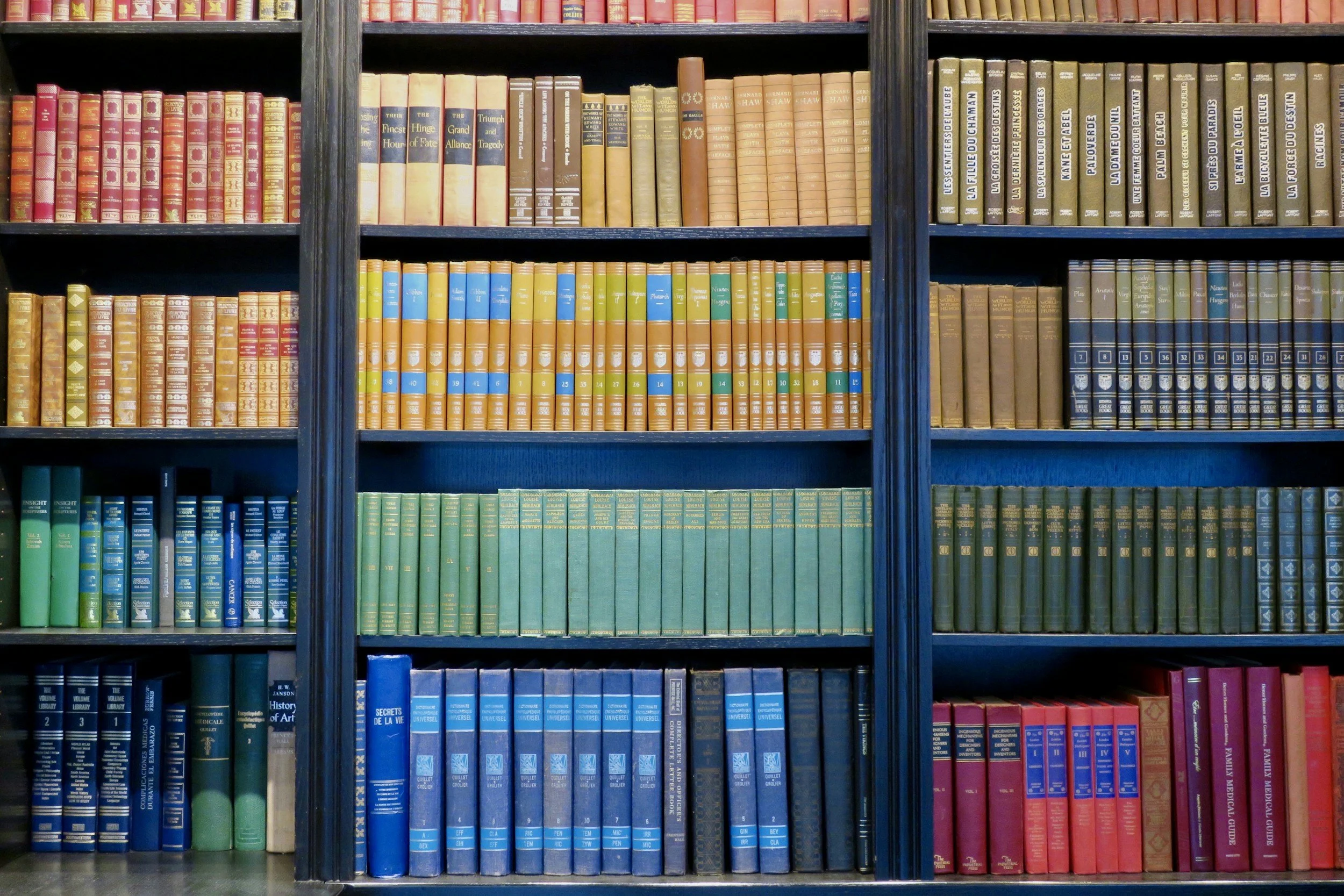 Bookshelves filled with colorful books arranged by color.