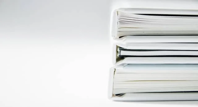 Three white stacks of paper or documents placed on a white surface.