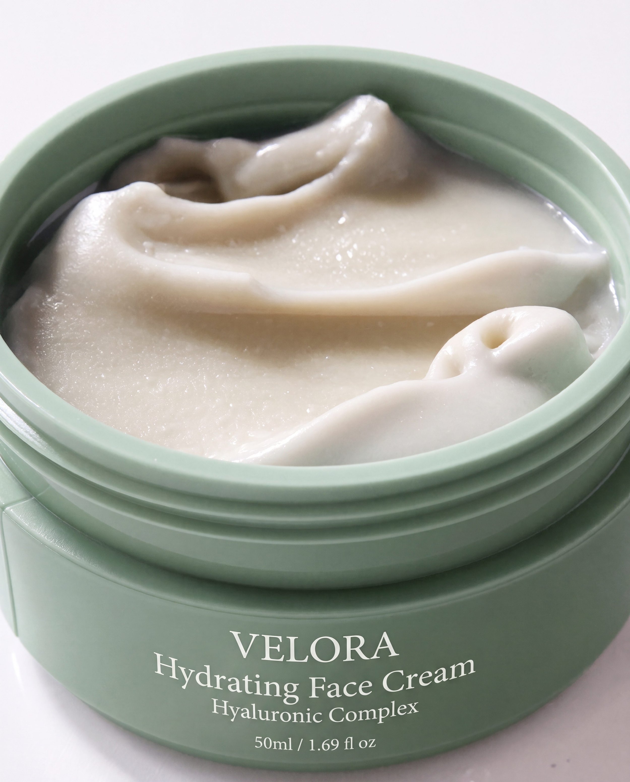 Close-up of a green container of Velora Hydrating Face Cream with a white creamy texture visible at the top.