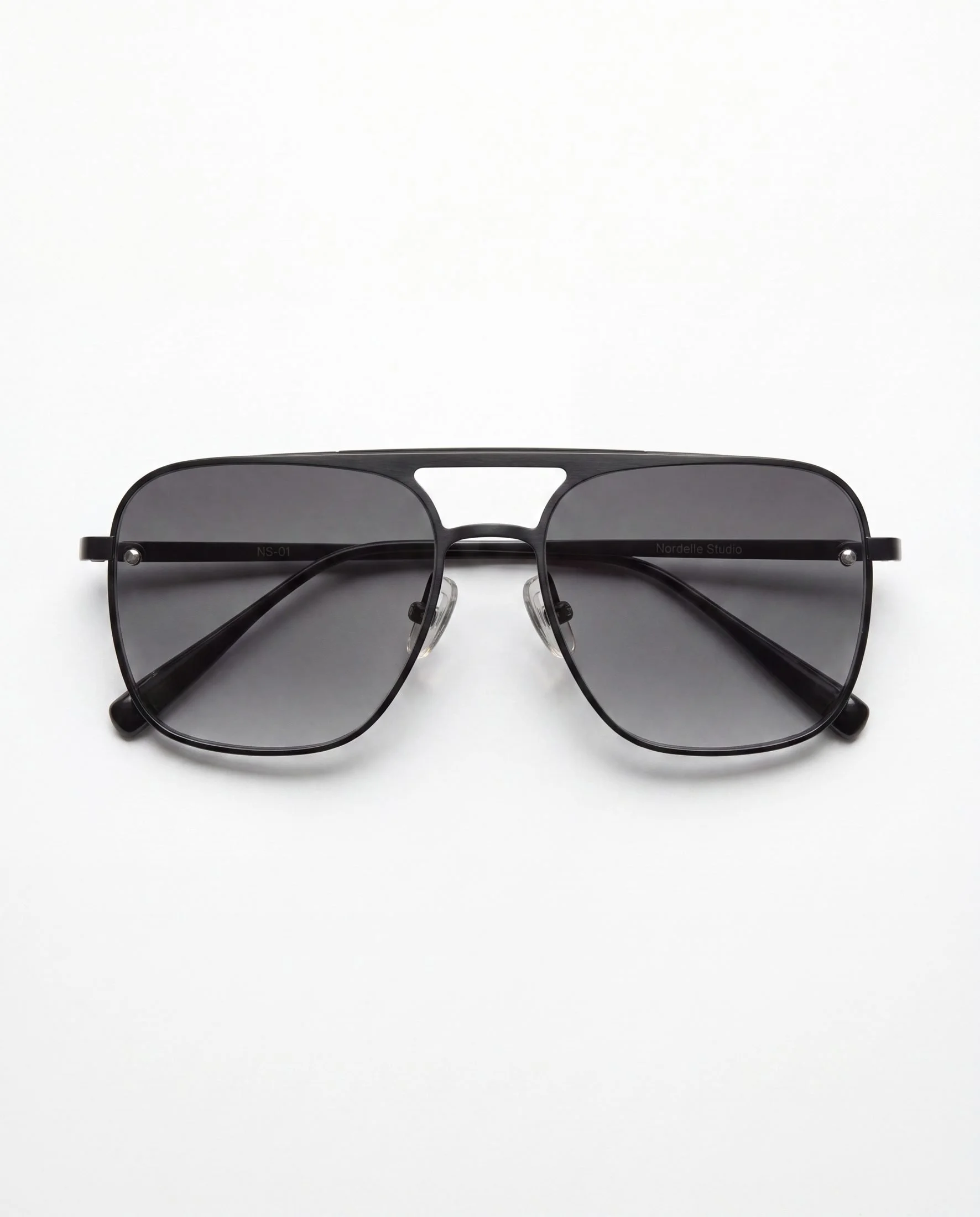 Black sunglasses with dark lenses resting on a white surface.