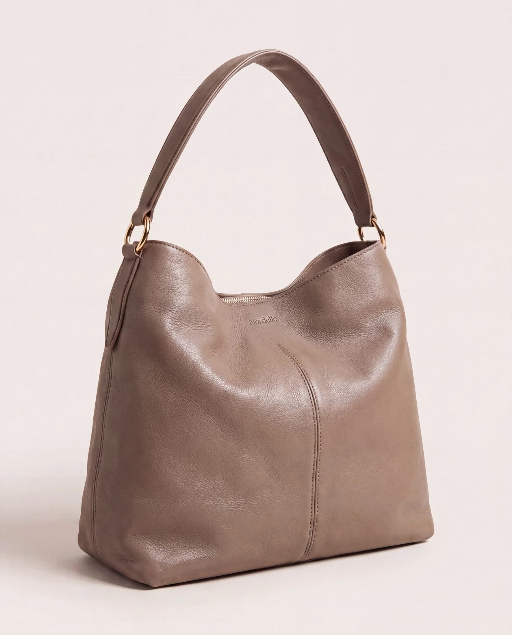 A taupe-colored leather handbag with a rounded body and a single strap handle, set against a plain white background.