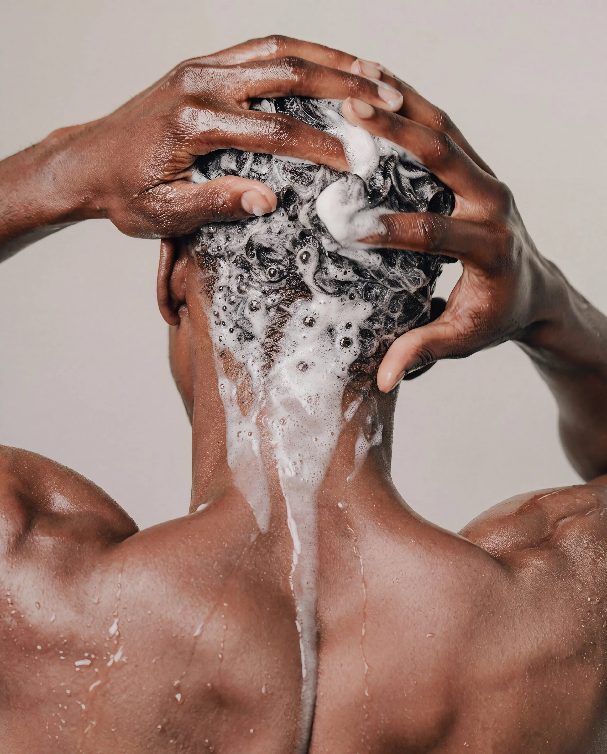 Close-up of a person washing their face with soap and water, with hands lathering soap on their face, foam visible.