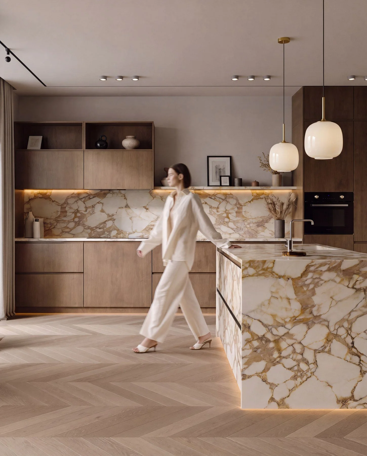 A woman wearing an off-white suit and high heels walking through a modern, minimalist kitchen with wood cabinetry, a marble island, and pendant lights.
