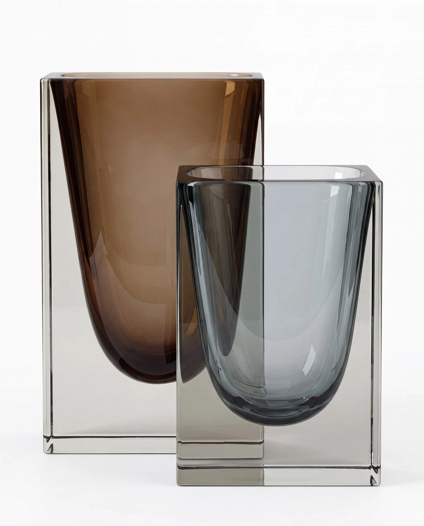 Two modern glass vases, one amber and one clear, positioned in front of a clear acrylic stand, against a white background.