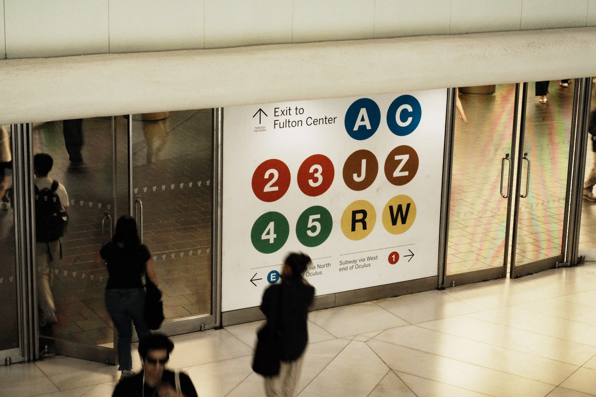 Large subway station sign indicating directions to the Fulton Center exit, with colorful circle symbols representing different subway lines.