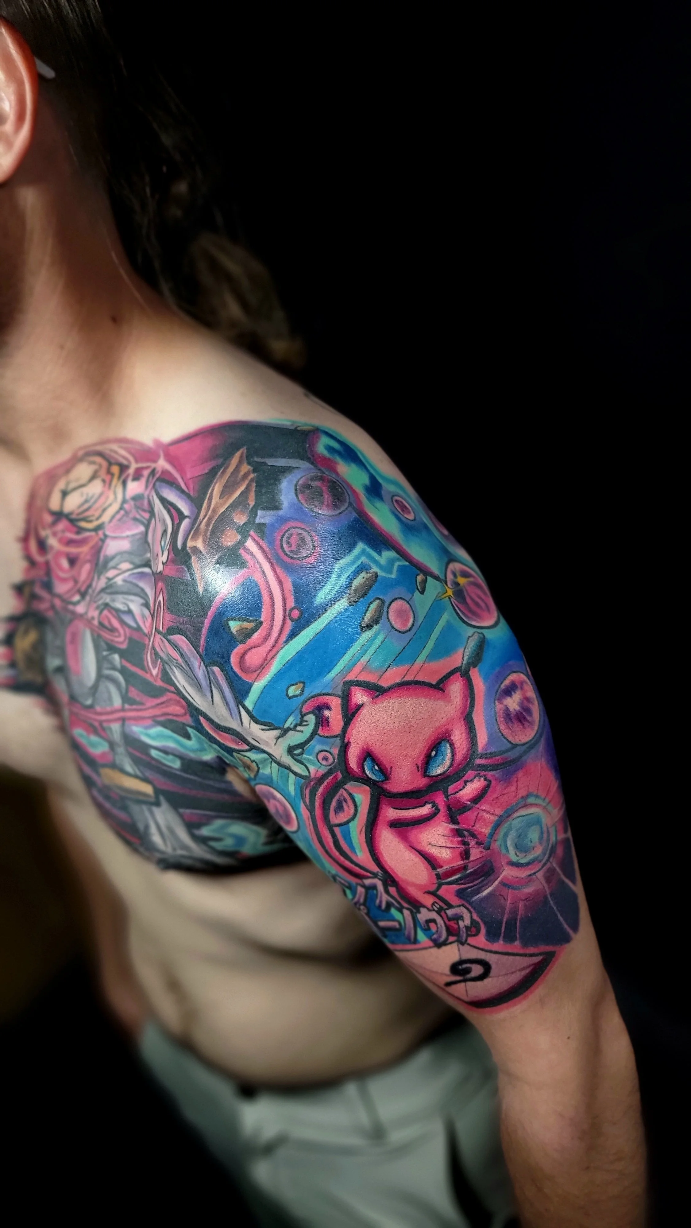 Colorful tattoo sleeve featuring Pikachu and abstract designs on a person's arm.