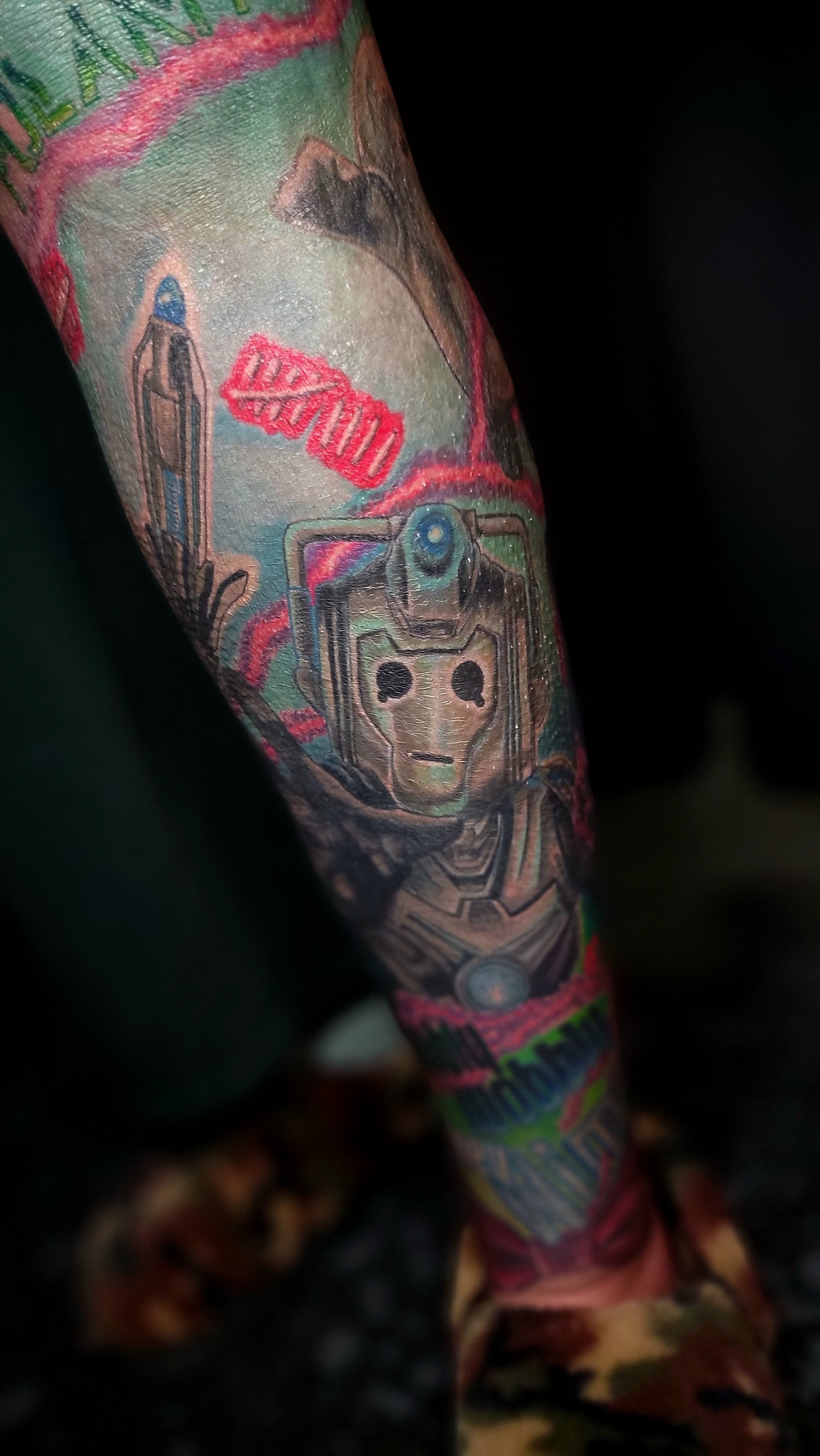 Close-up of a colorful tattoo sleeve featuring a robot or android head with mechanical details and a skull-like face.