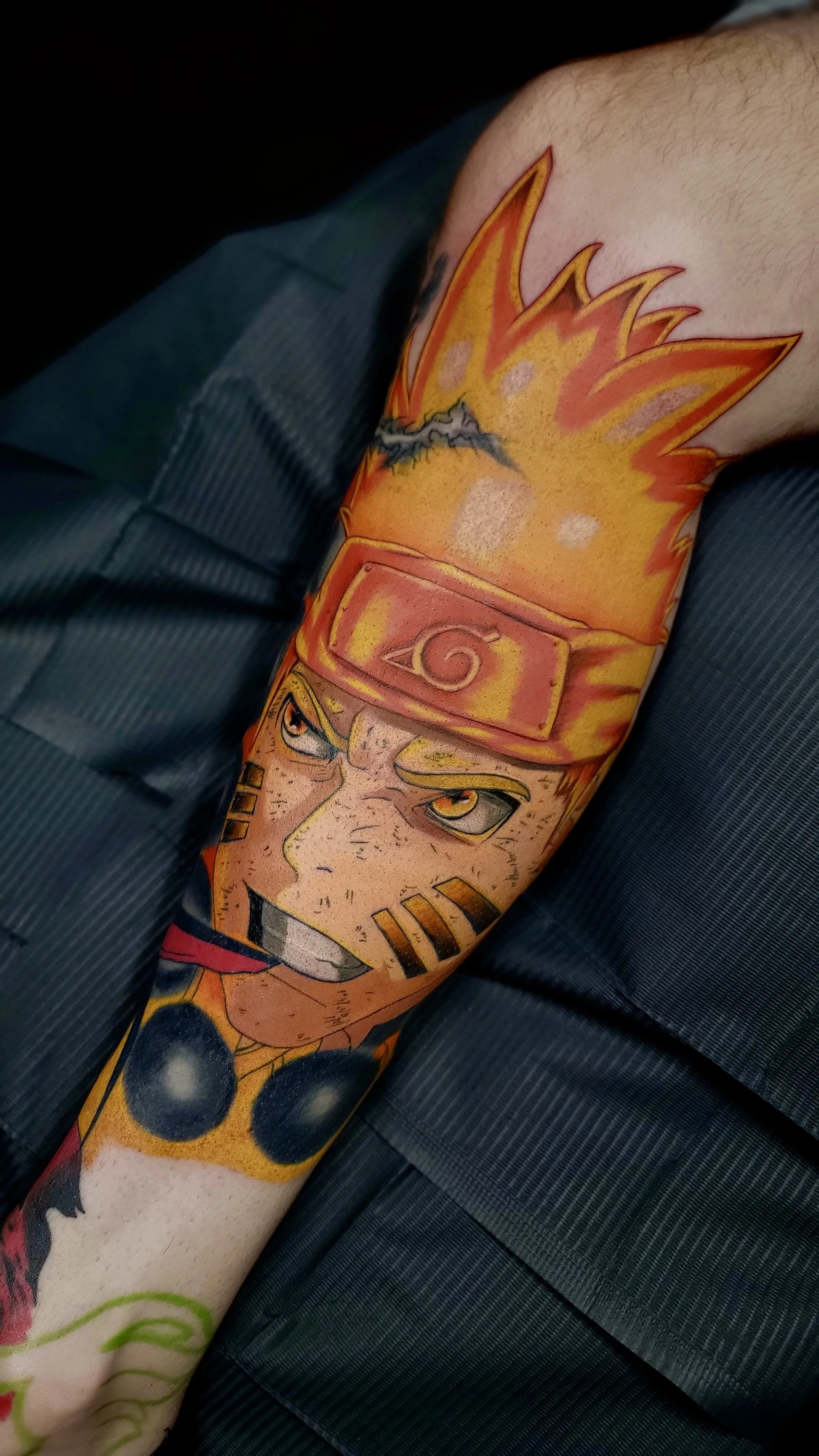 Close-up of a tattoo sleeve featuring Naruto Uzumaki, a character from the anime Naruto, with spiky blond hair, a forehead protector, and an intense expression.