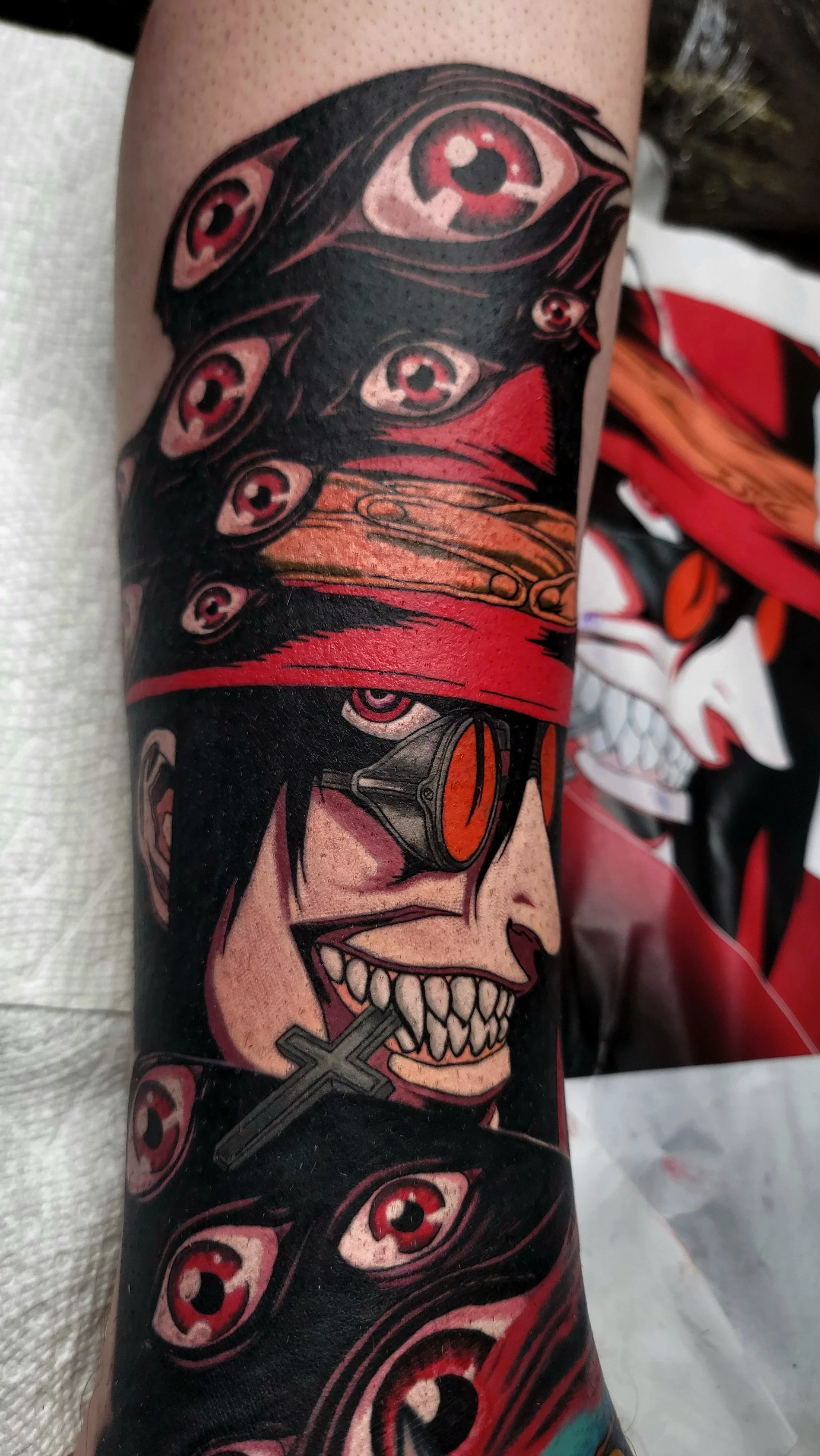 Tattoo of a woman with dark hair and red headband, with multiple eyes and skulls in a comic or graffiti style.