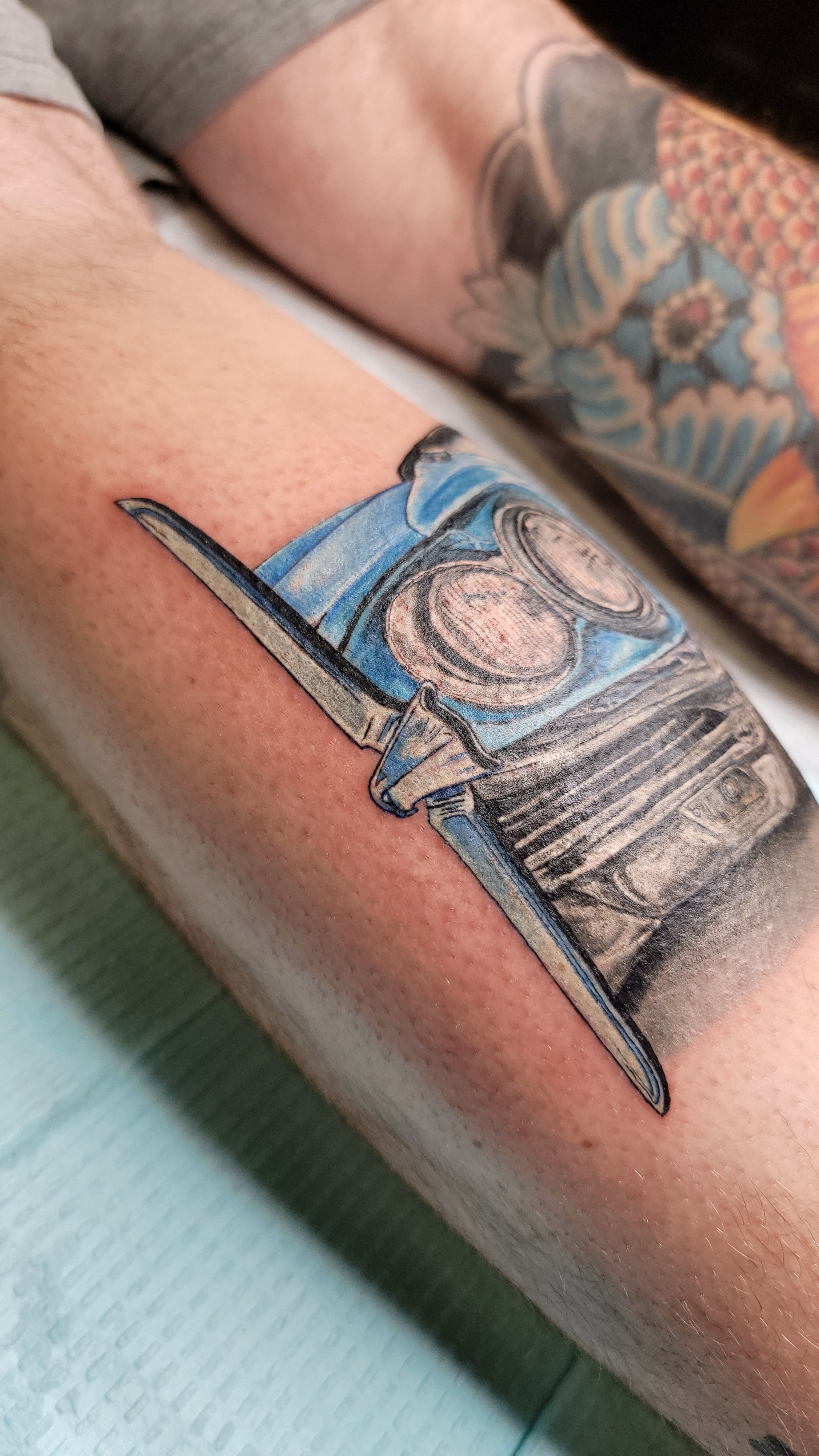 Colorful tattoo of a vintage car on a person's arm.