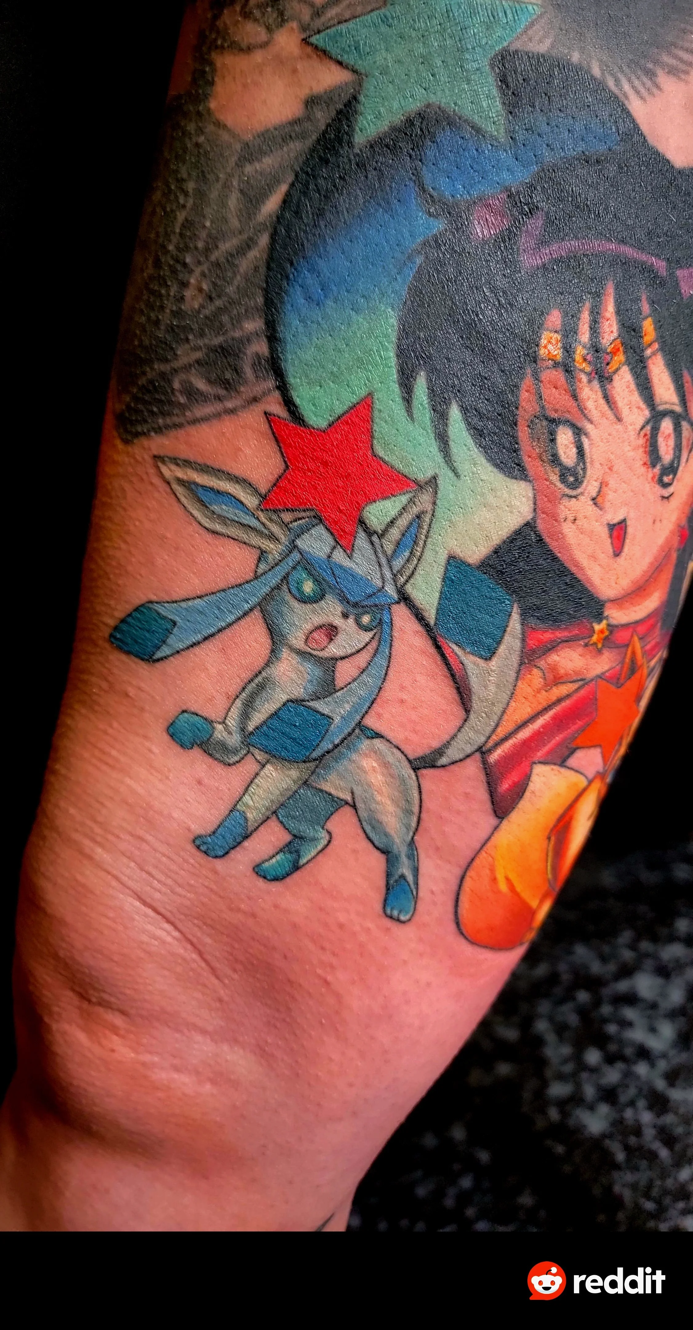A colorful tattoo of Pikachu, a Pokémon character, with a red star on its forehead, accompanied by a girl with short black hair and expressive eyes, holding a lit dynamite stick.