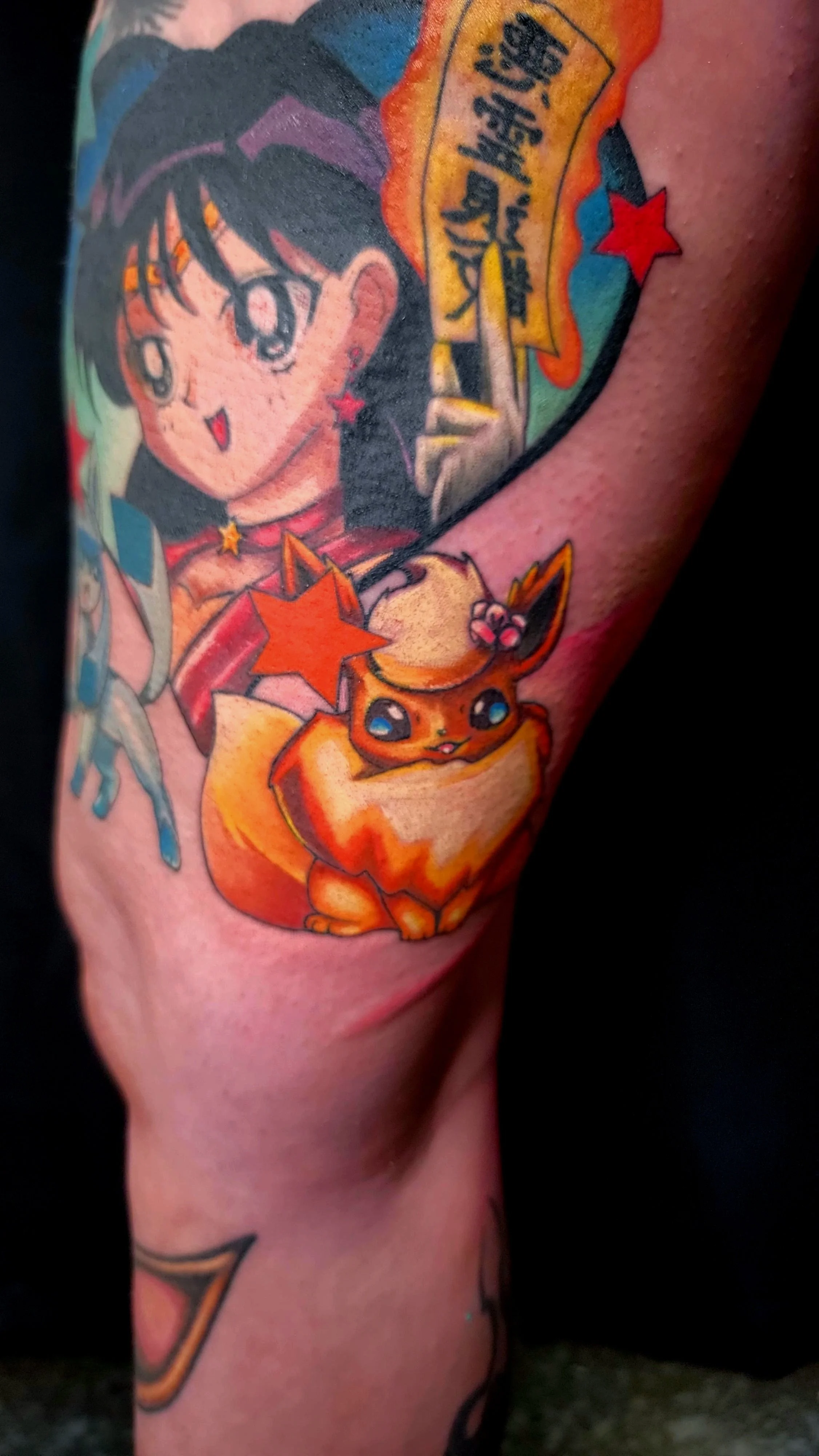 Colorful tattoo featuring two anime-style characters, a girl with black hair and a fox, with stars and text in Japanese.