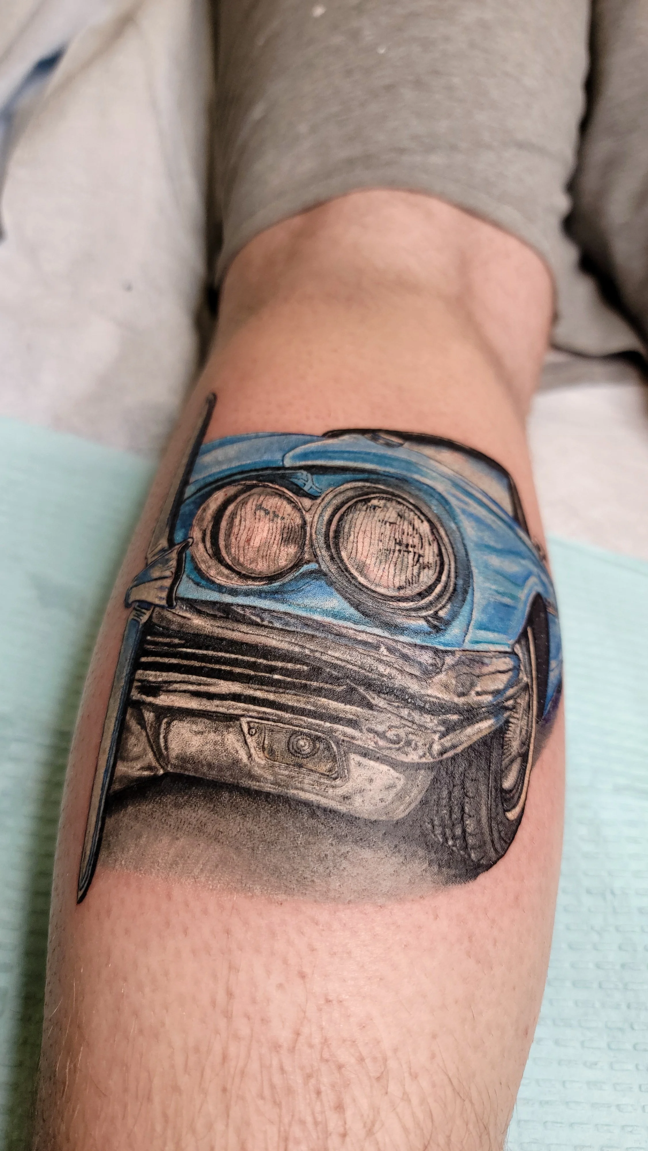 Tattoo of a classic blue car on a person's thigh.